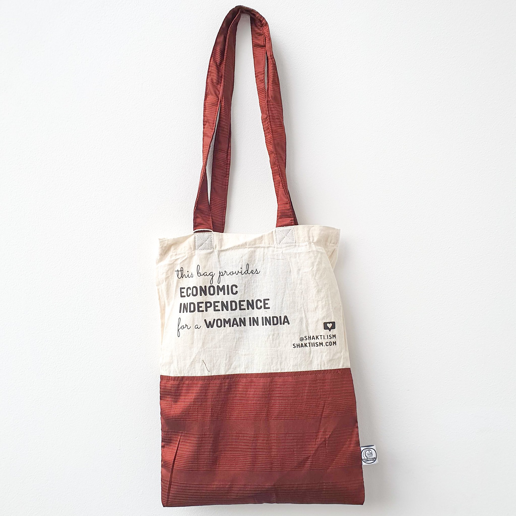 A vibrant Independence sari tote bag handcrafted from repurposed sari fabric, showcasing unique patterns and colors, with a message promoting women's economic independence.