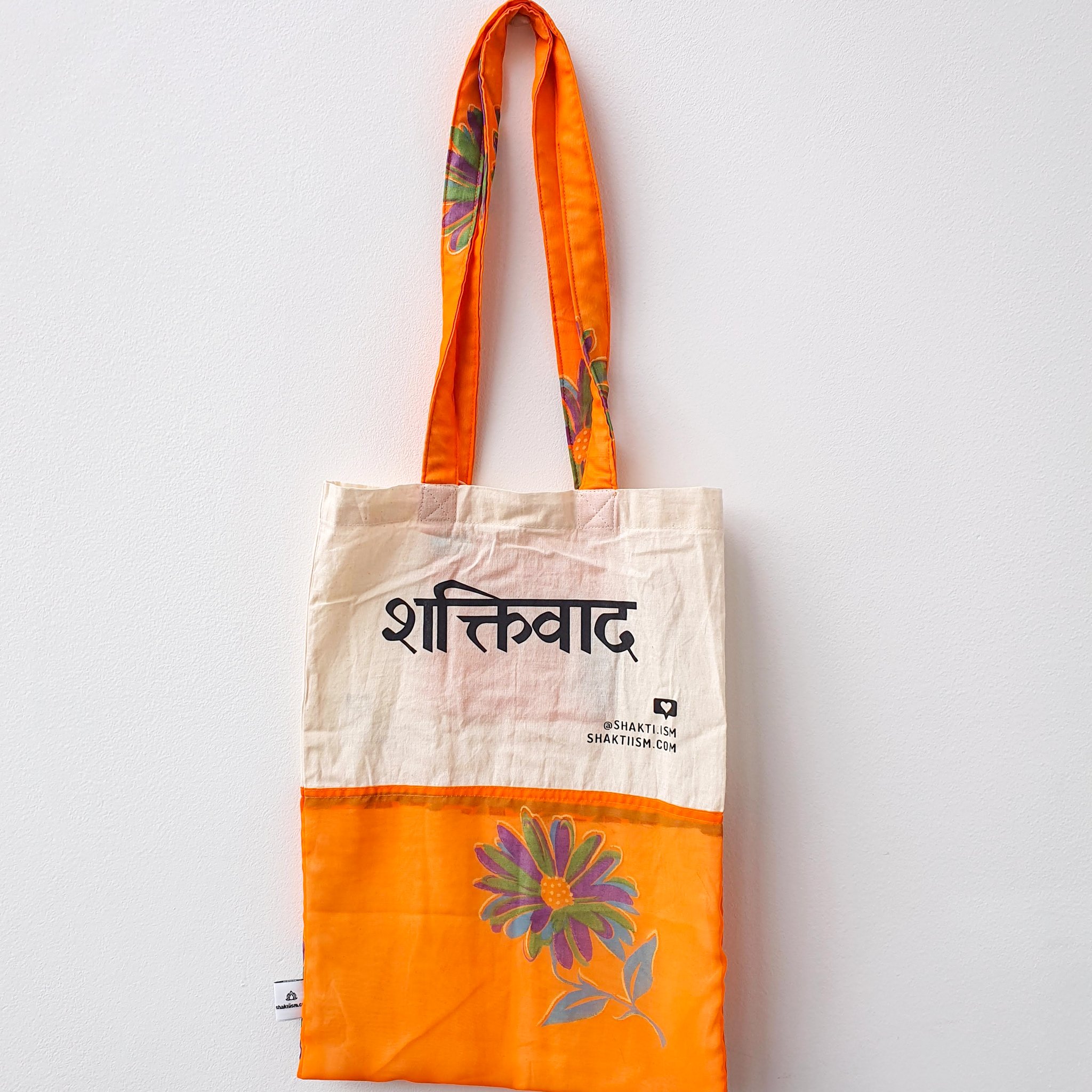 A vibrant Independence sari tote bag handcrafted from repurposed sari fabric, showcasing unique patterns and colors, with a message promoting women's economic independence.