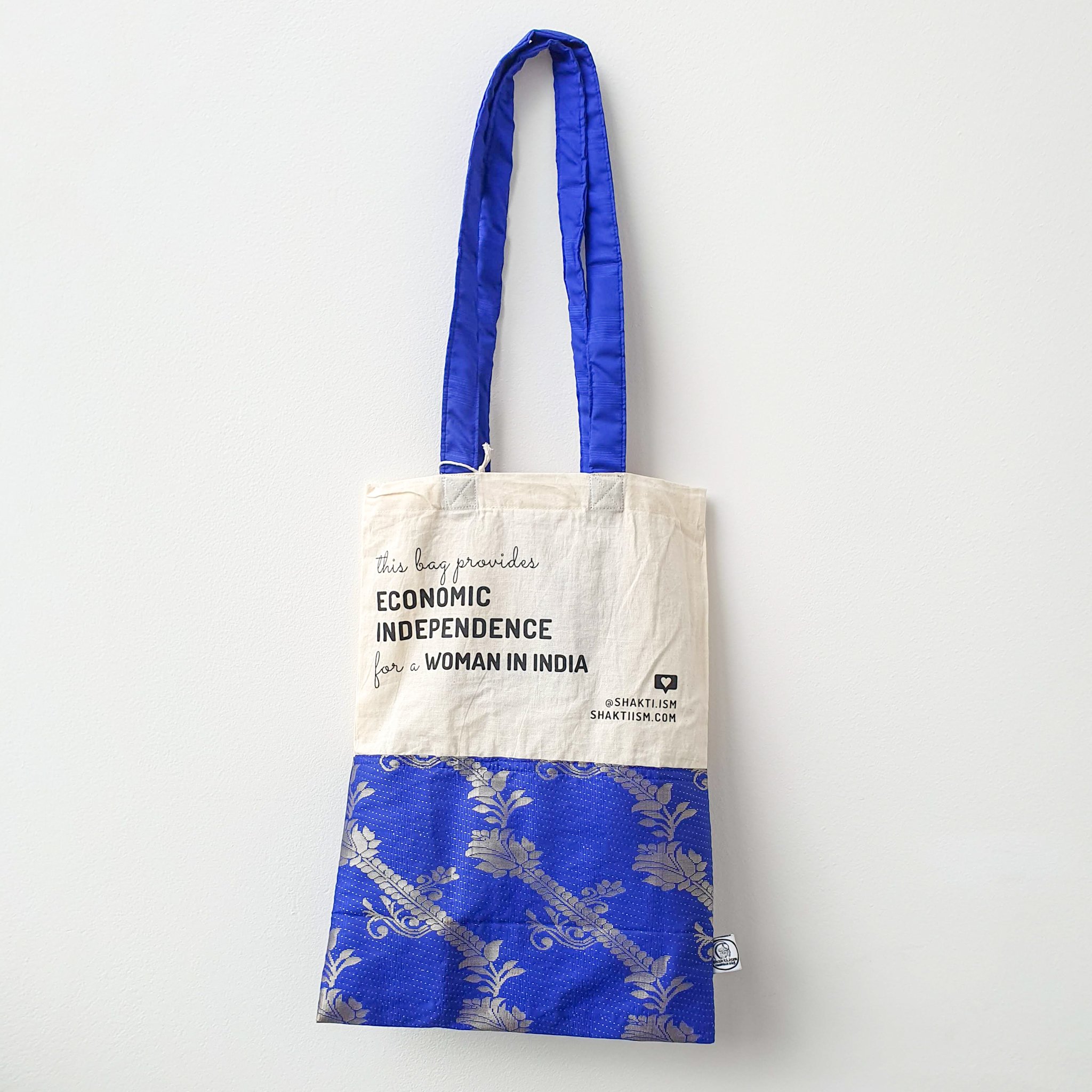 A vibrant Independence sari tote bag handcrafted from repurposed sari fabric, showcasing unique patterns and colors, with a message promoting women's economic independence.