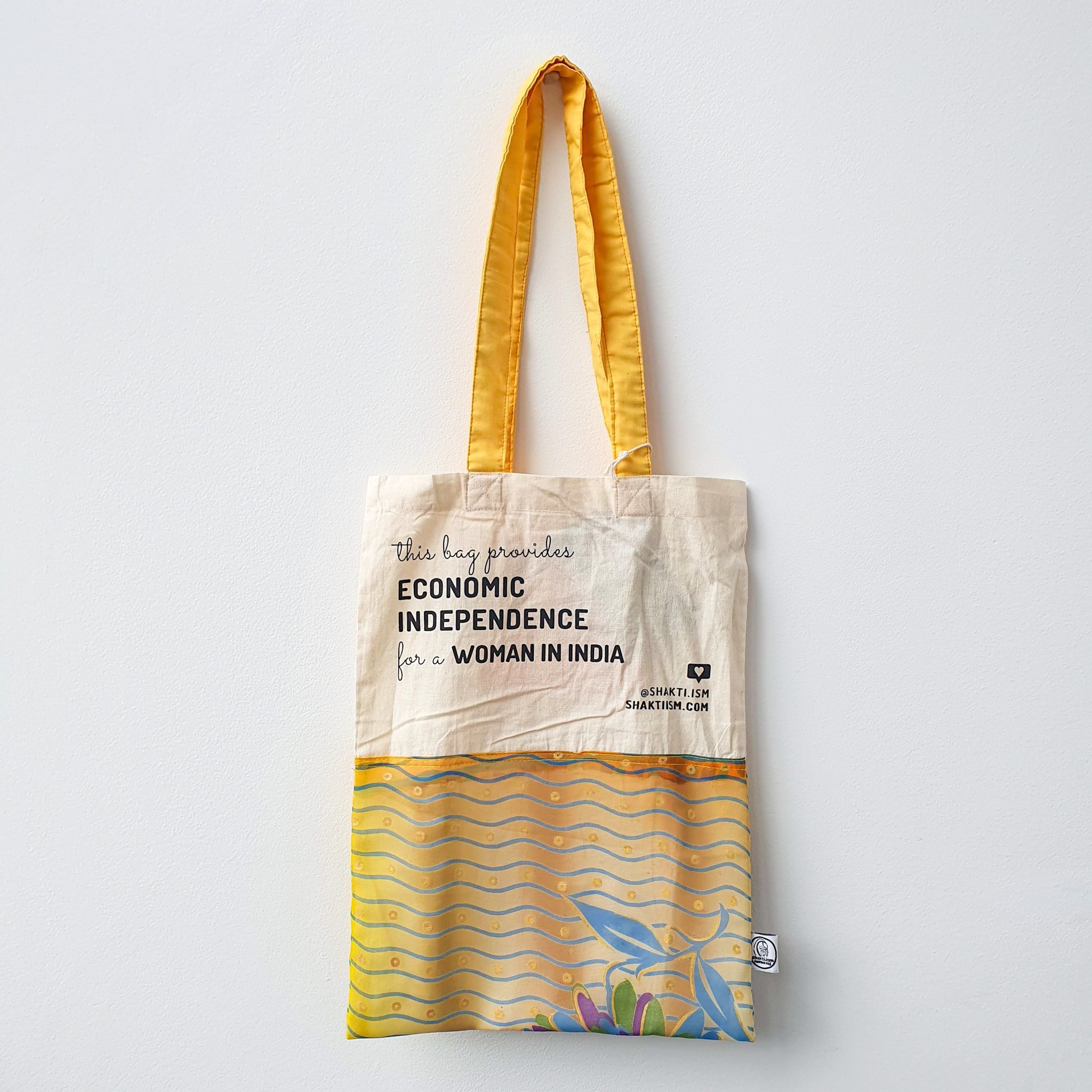 A vibrant Independence sari tote bag handcrafted from repurposed sari fabric, showcasing unique patterns and colors, with a message promoting women's economic independence.