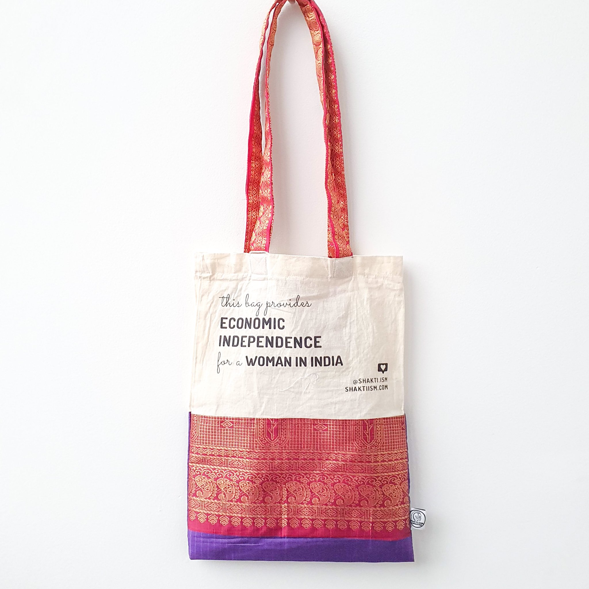 A vibrant Independence sari tote bag handcrafted from repurposed sari fabric, showcasing unique patterns and colors, with a message promoting women's economic independence.