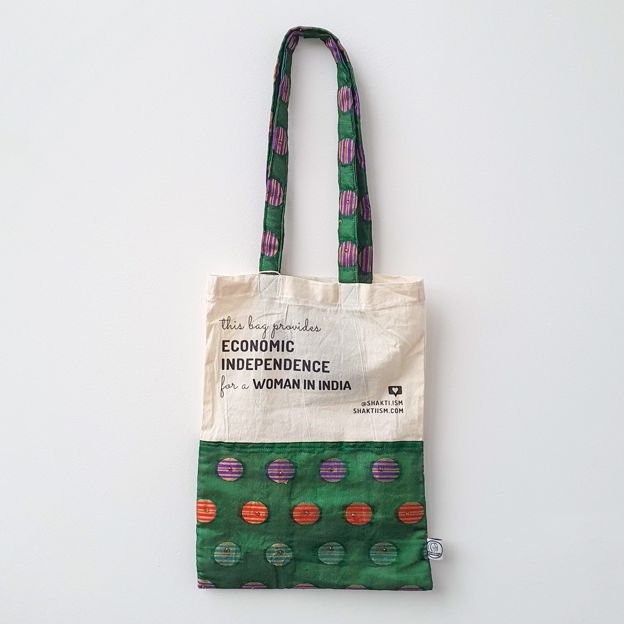 A vibrant Independence sari tote bag handcrafted from repurposed sari fabric, showcasing unique patterns and colors, with a message promoting women's economic independence.