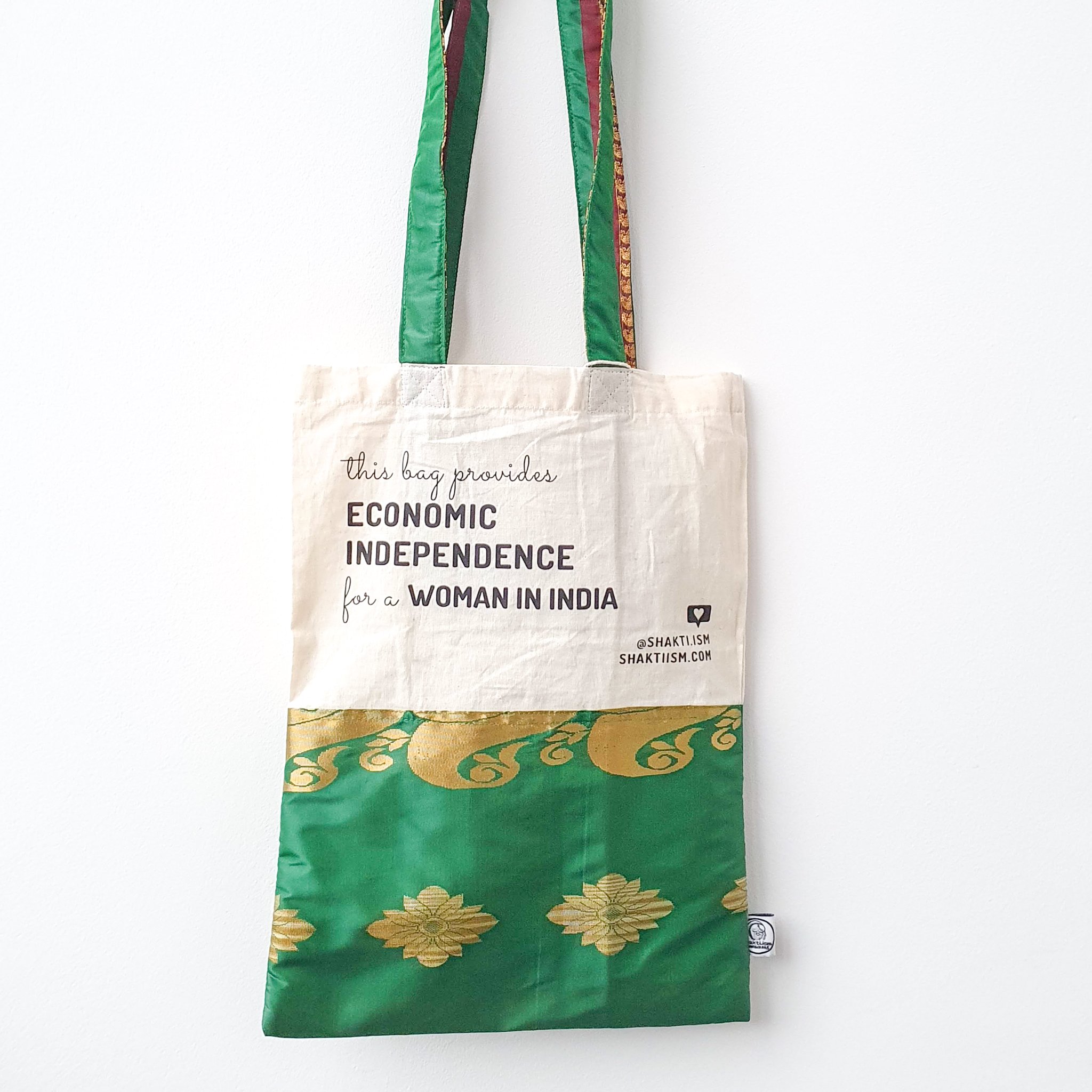 A vibrant Independence sari tote bag handcrafted from repurposed sari fabric, showcasing unique patterns and colors, with a message promoting women's economic independence.