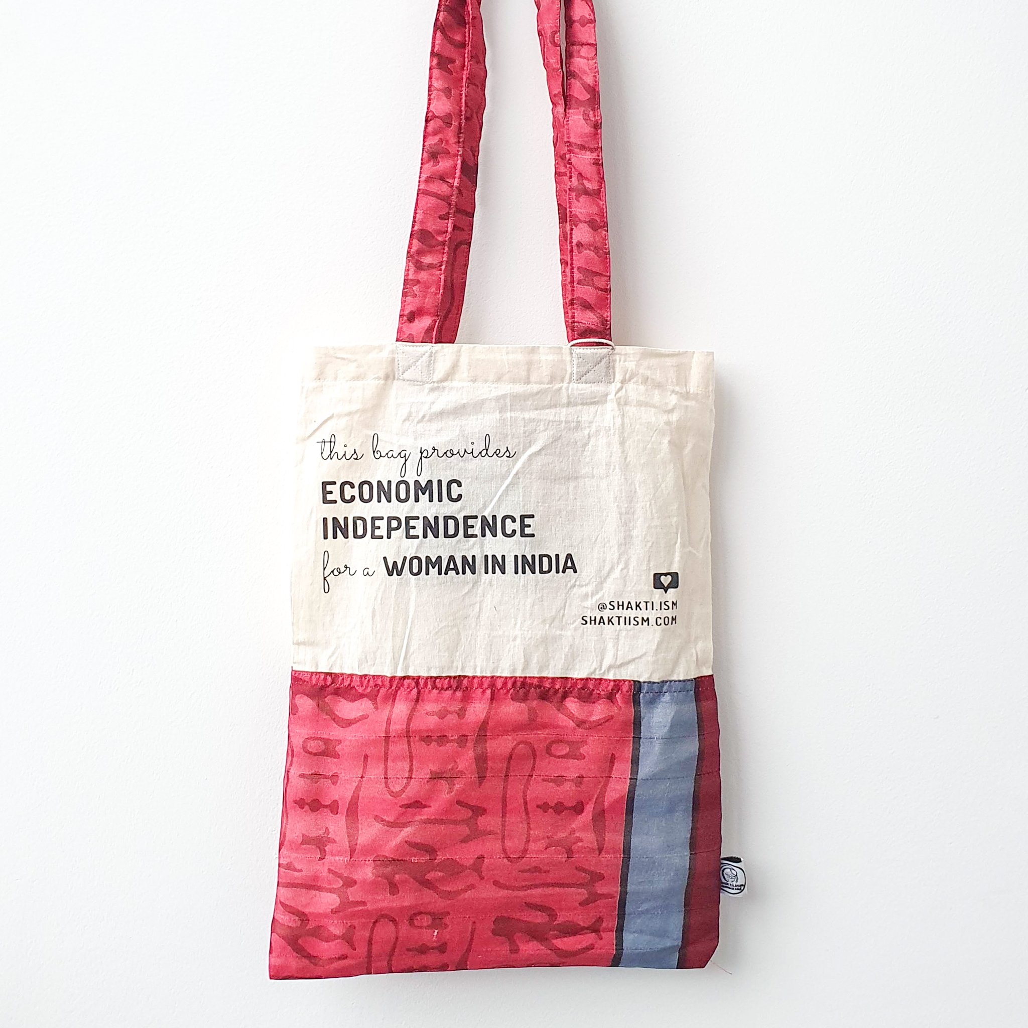 A vibrant Independence sari tote bag handcrafted from repurposed sari fabric, showcasing unique patterns and colors, with a message promoting women's economic independence.