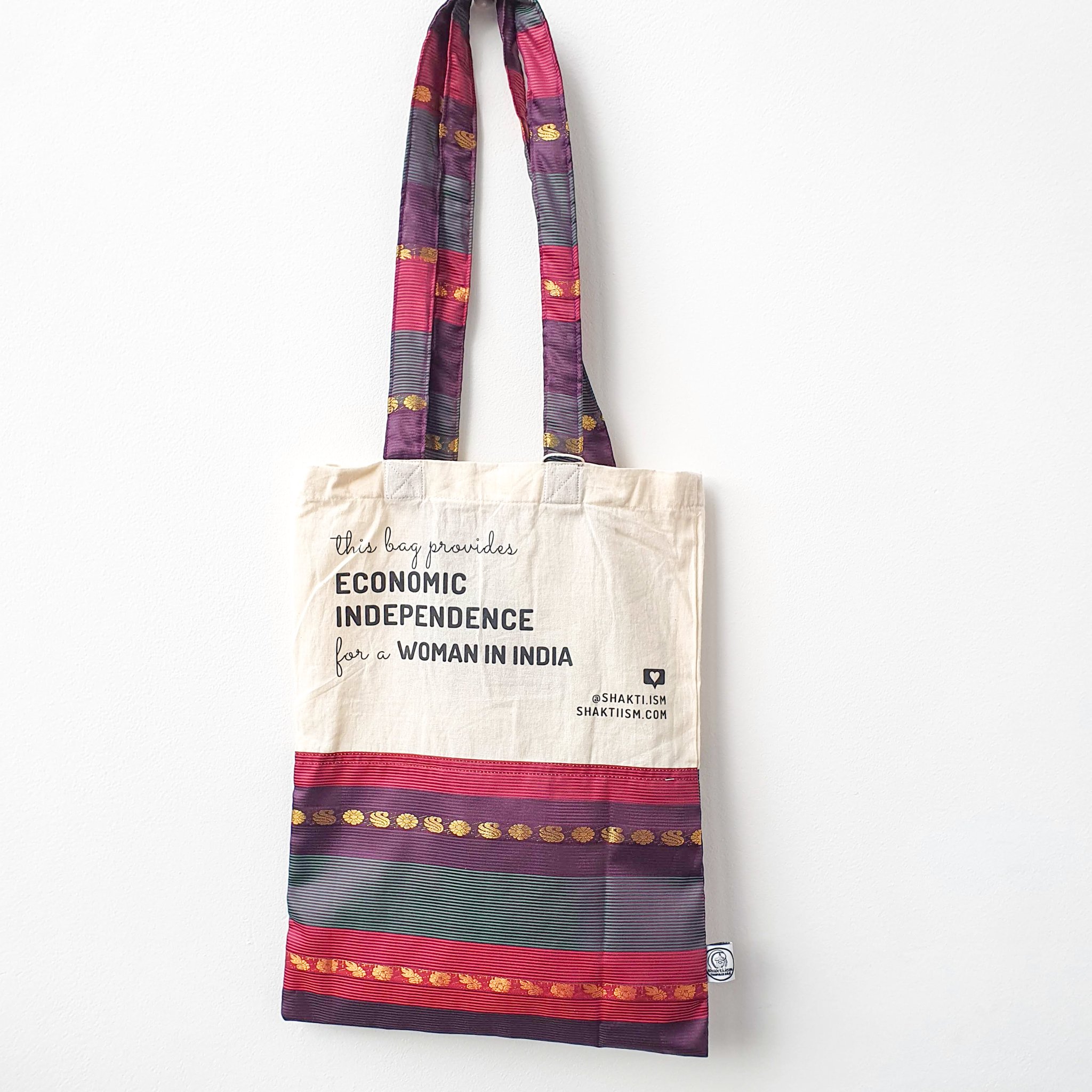 A vibrant Independence sari tote bag handcrafted from repurposed sari fabric, showcasing unique patterns and colors, with a message promoting women's economic independence.