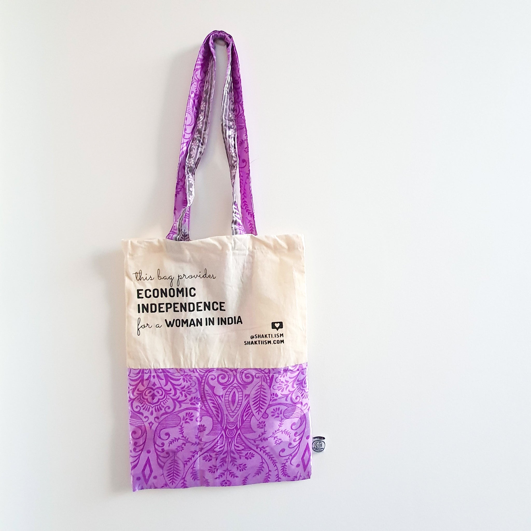 A vibrant Independence sari tote bag handcrafted from repurposed sari fabric, showcasing unique patterns and colors, with a message promoting women's economic independence.