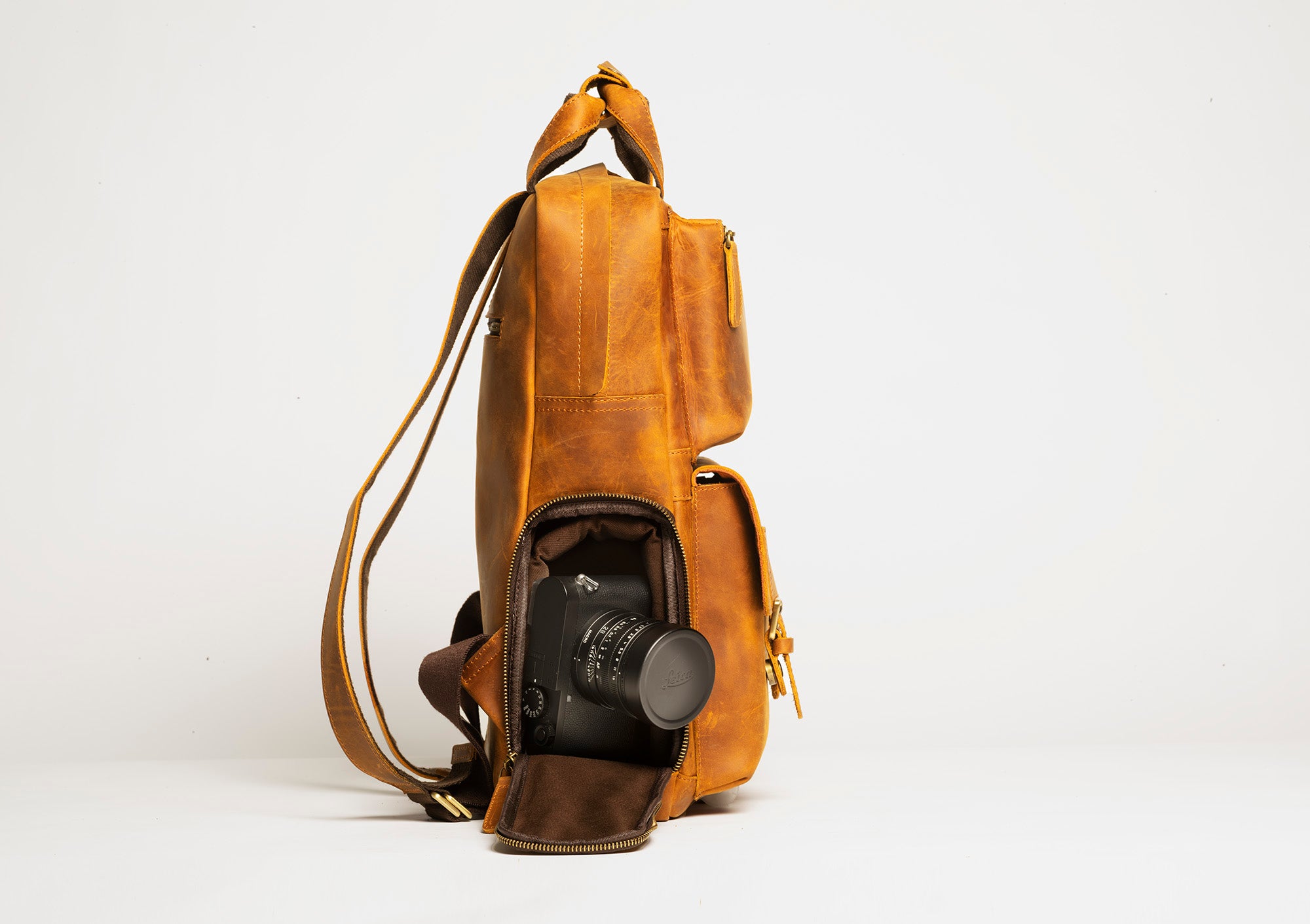 The MANN Bag, a large capacity leather camera backpack, showcasing its sleek design, padded compartments, and adjustable straps.