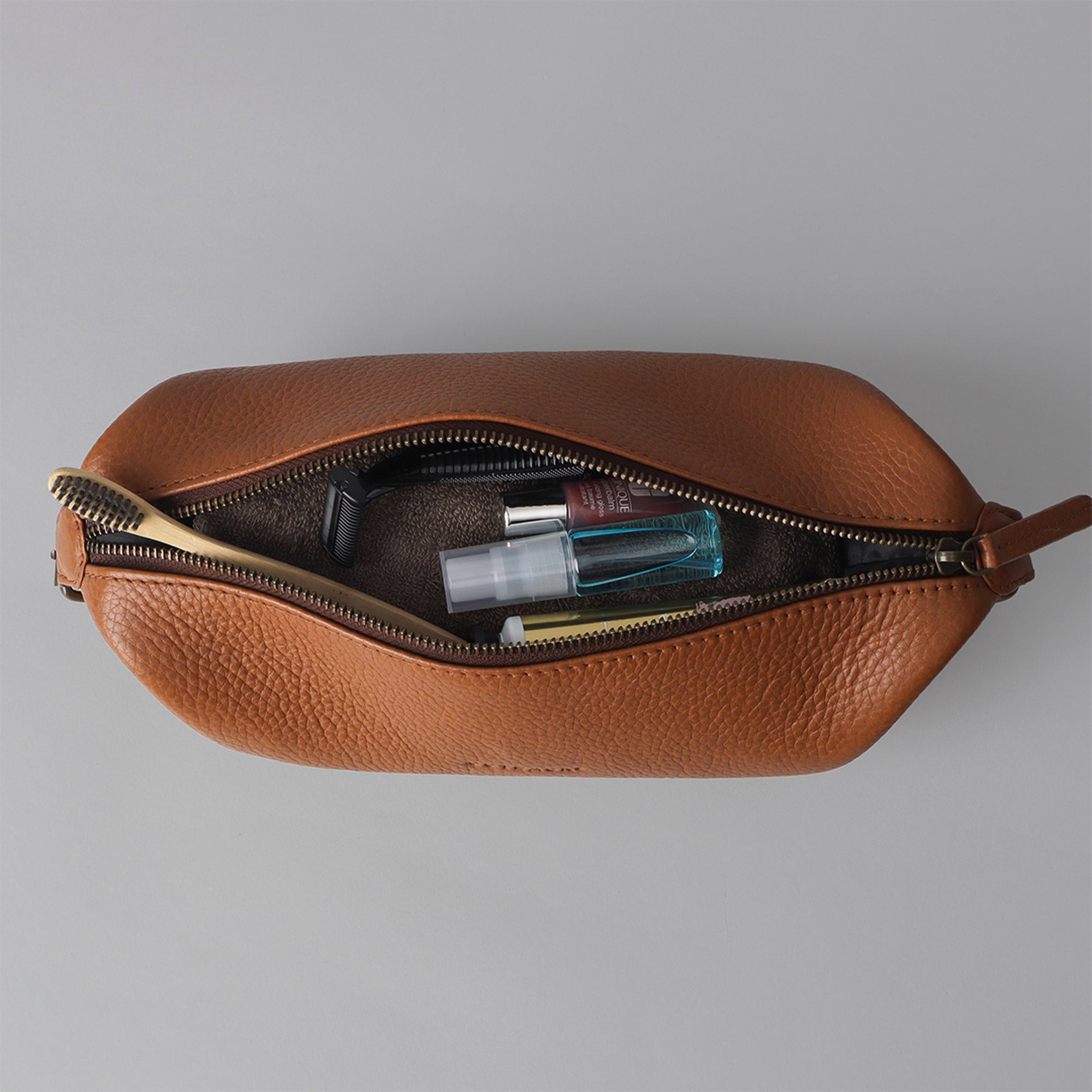 Tokyo Toilet Bag made of premium full grain leather, featuring a spacious interior, zipper pocket, and antique brass hardware.