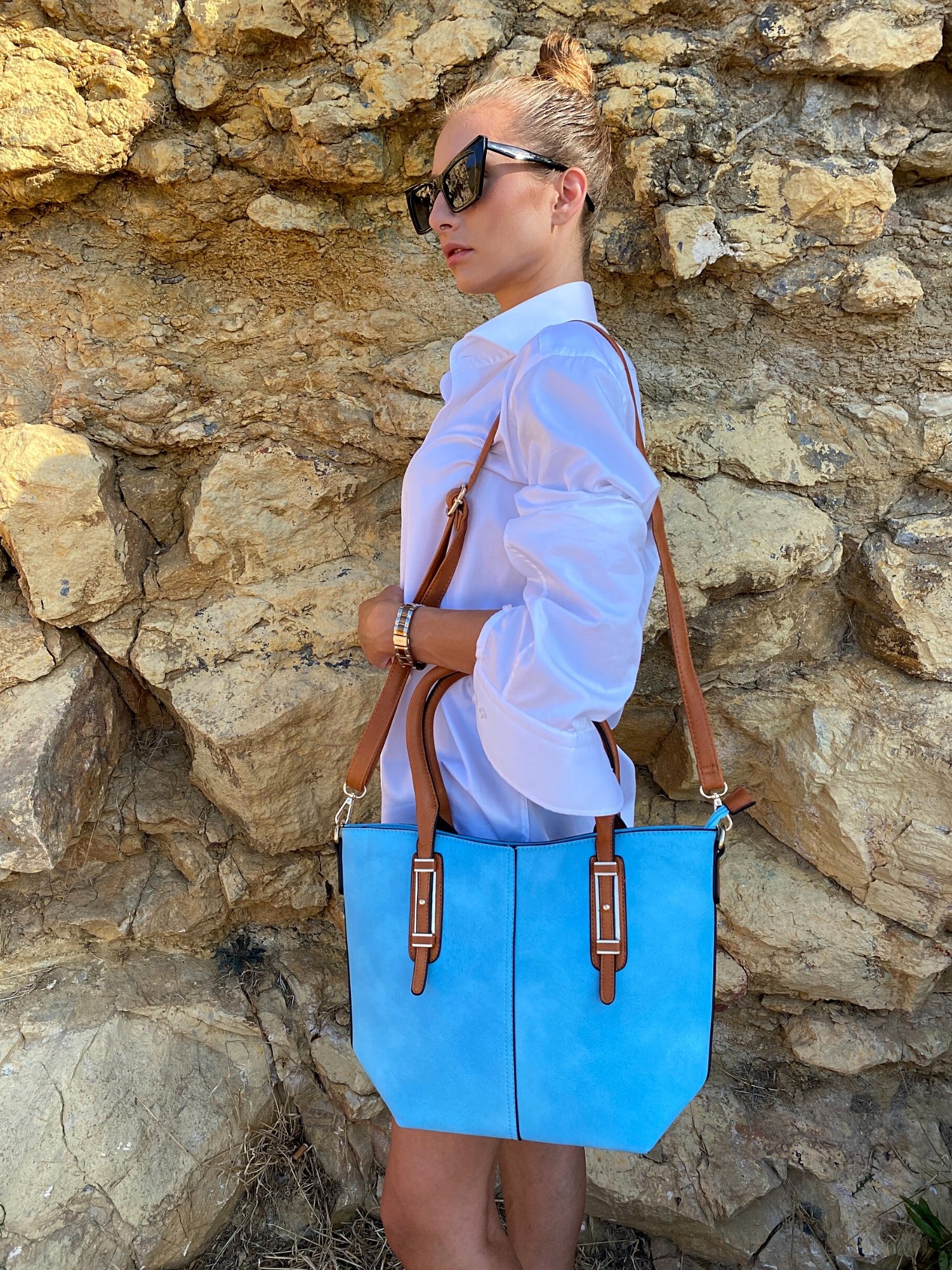 Light blue tote bag with zip closure, metallic details, and adjustable shoulder strap.