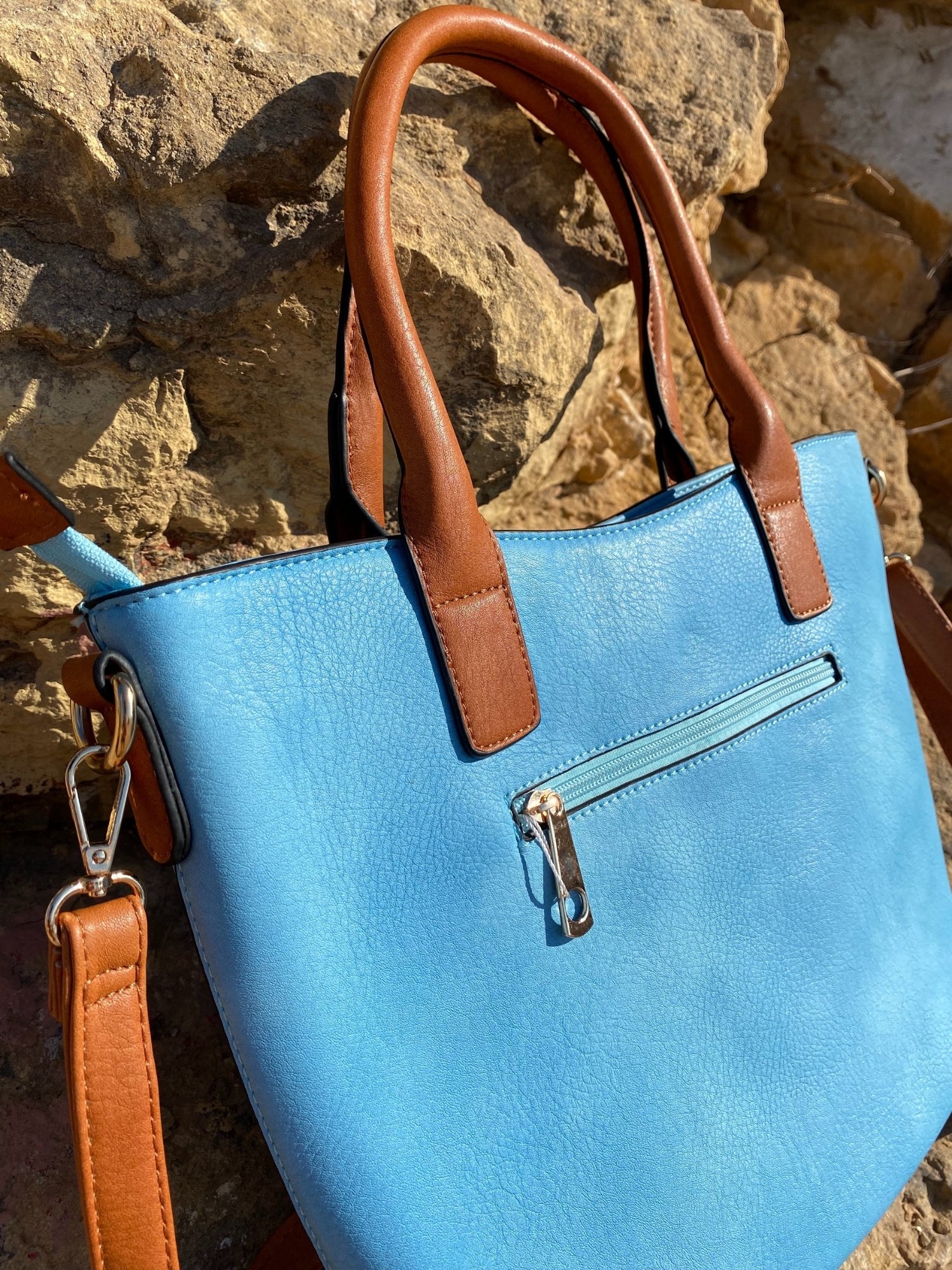 Light blue tote bag with zip closure, metallic details, and adjustable shoulder strap.