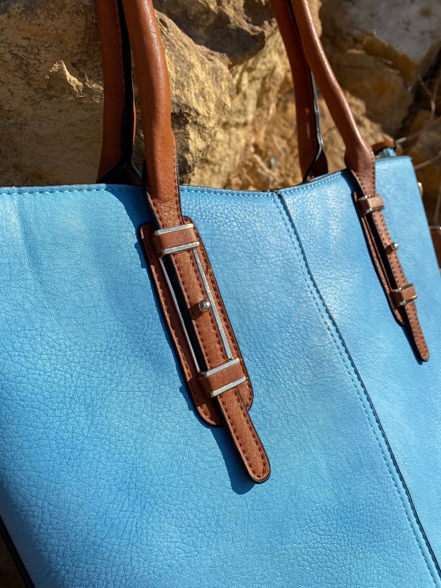 Light blue tote bag with zip closure, metallic details, and adjustable shoulder strap.