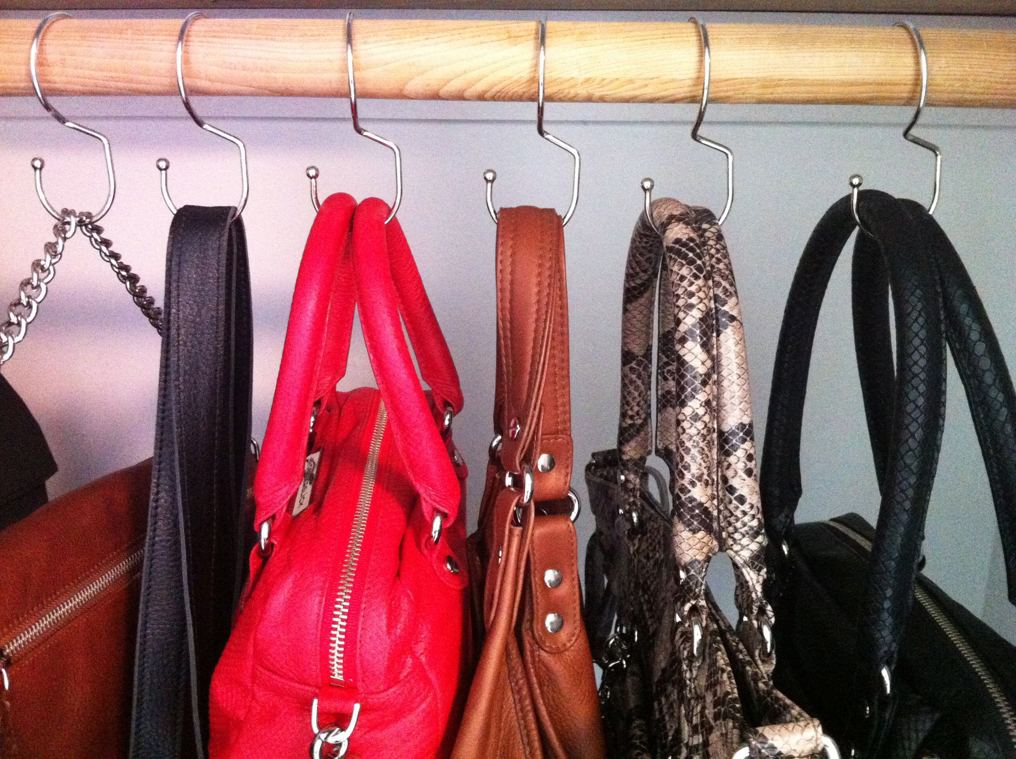 Tote Hanger® hooks elegantly displaying handbags on a clothing rod, showcasing their stylish design and functionality.