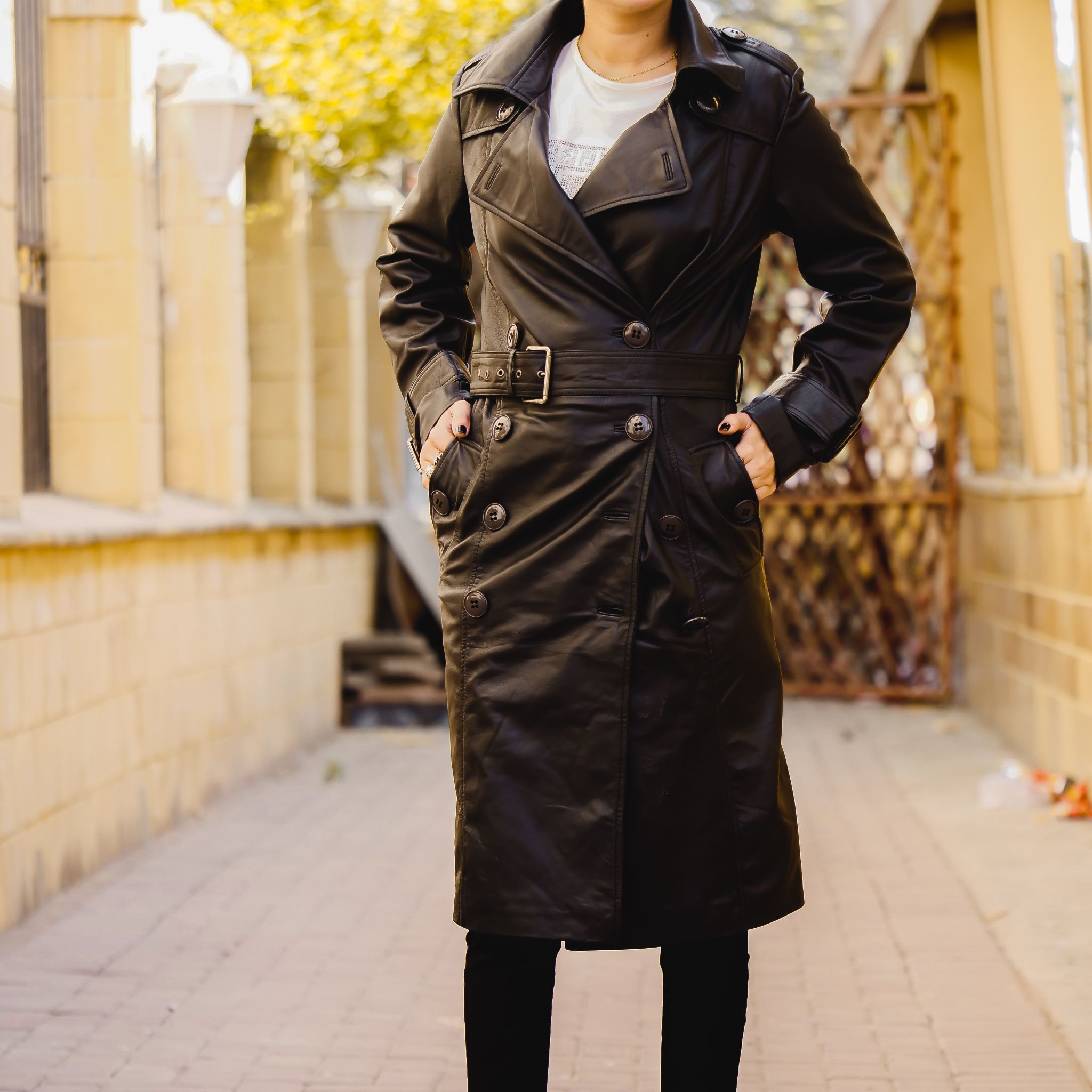 A stylish Women's Leather Long Coat in Black, featuring a double-breasted design and adjustable belt, made from 100% real lambskin leather.