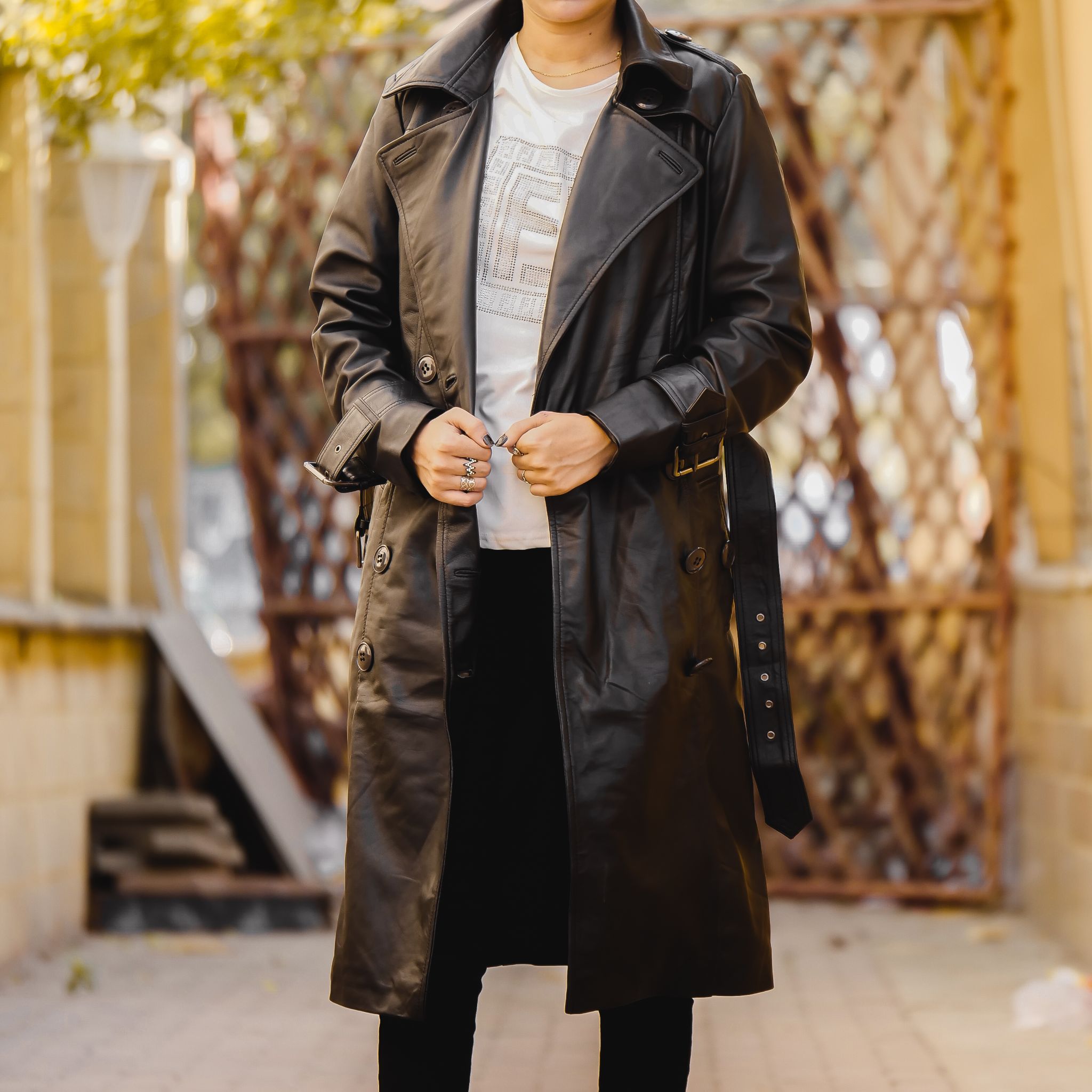 A stylish Women's Leather Long Coat in Black, featuring a double-breasted design and adjustable belt, made from 100% real lambskin leather.