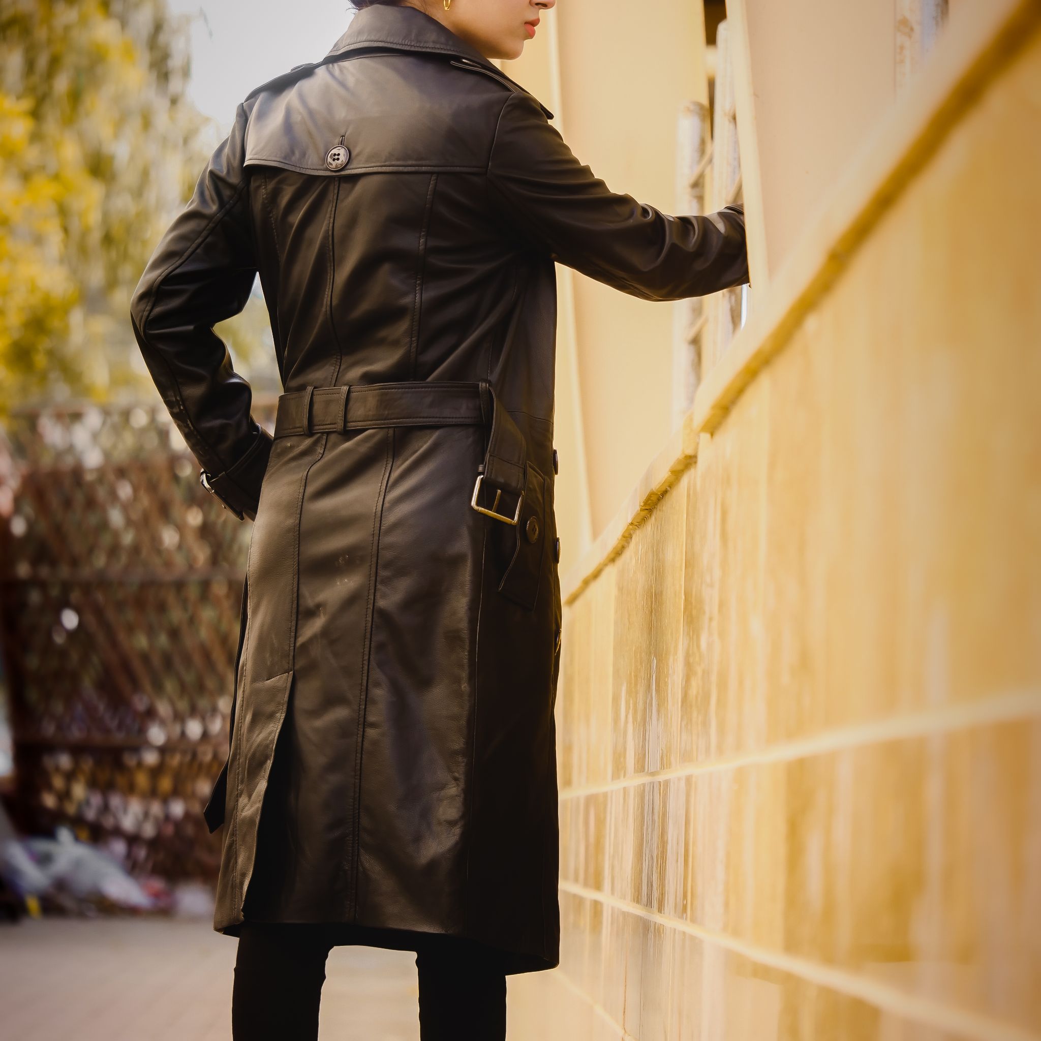 A stylish Women's Leather Long Coat in Black, featuring a double-breasted design and adjustable belt, made from 100% real lambskin leather.