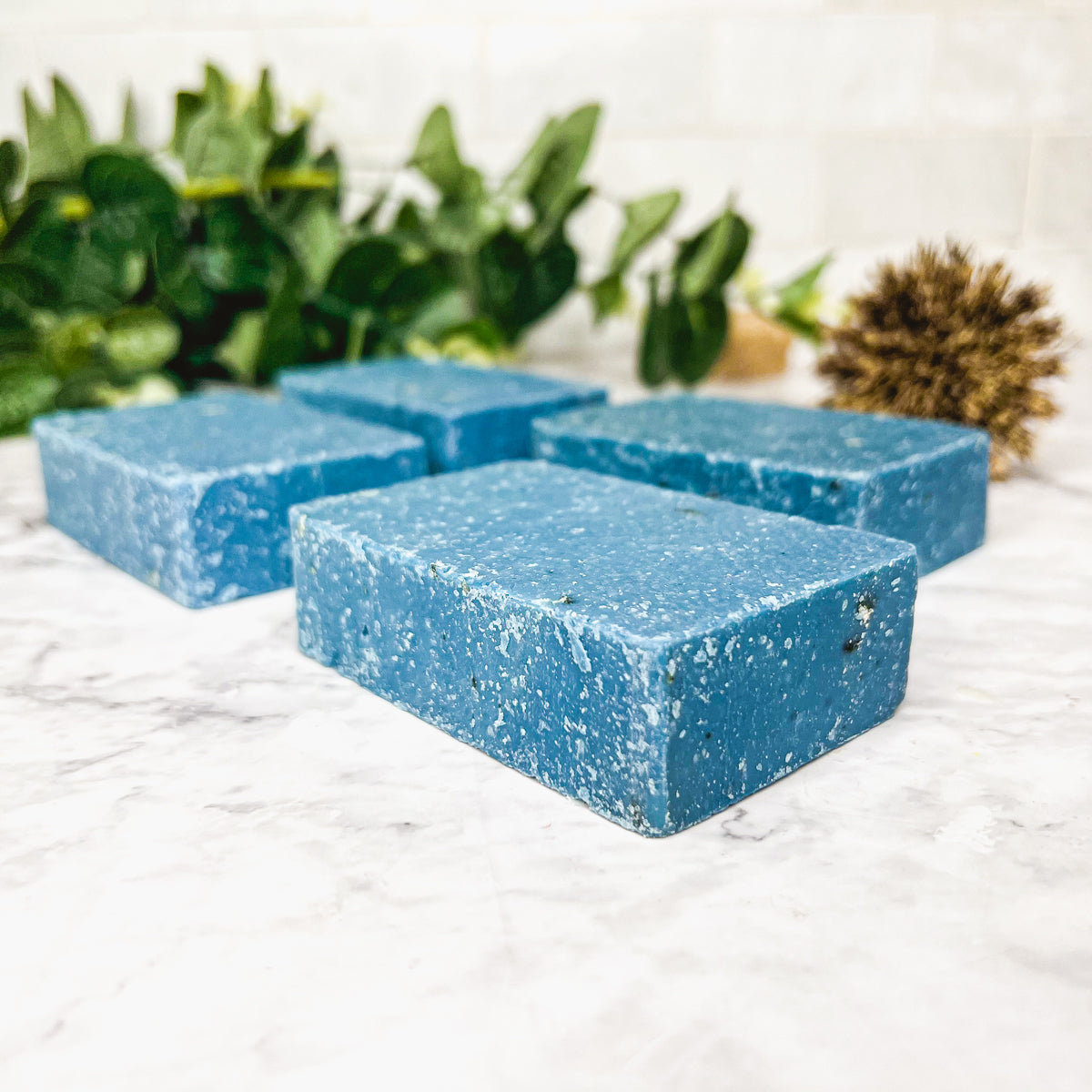 A vibrant blue bar of Blueberry Scrub soap with visible oatmeal and sea salt, showcasing its handcrafted design and rich color.