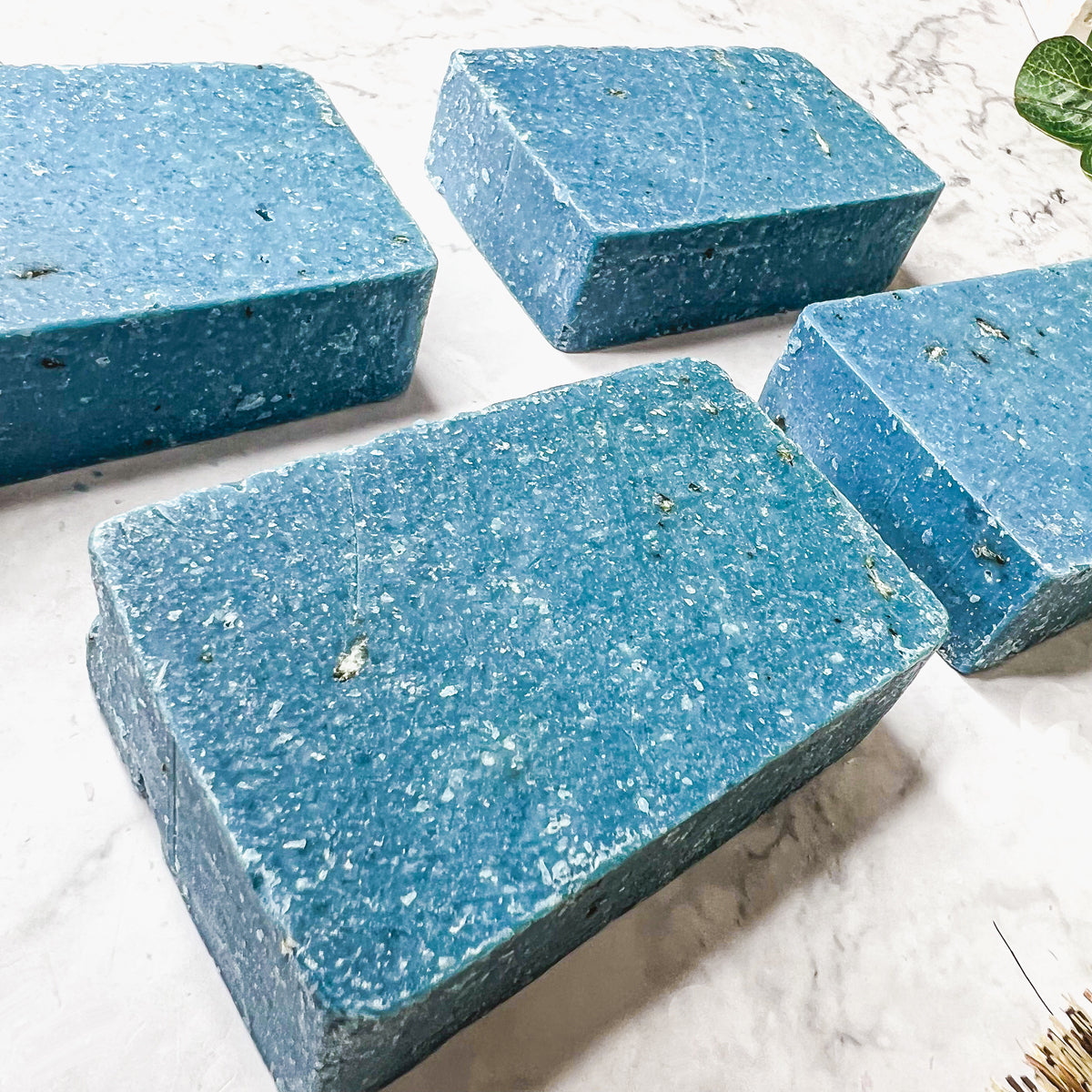 A vibrant blue bar of Blueberry Scrub soap with visible oatmeal and sea salt, showcasing its handcrafted design and rich color.