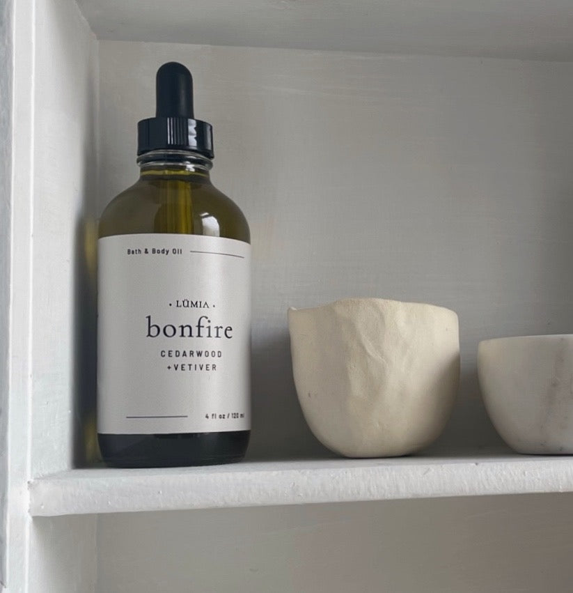 Bonfire Bath & Body Oil bottle with earthy design, showcasing its natural ingredients and soothing aroma.