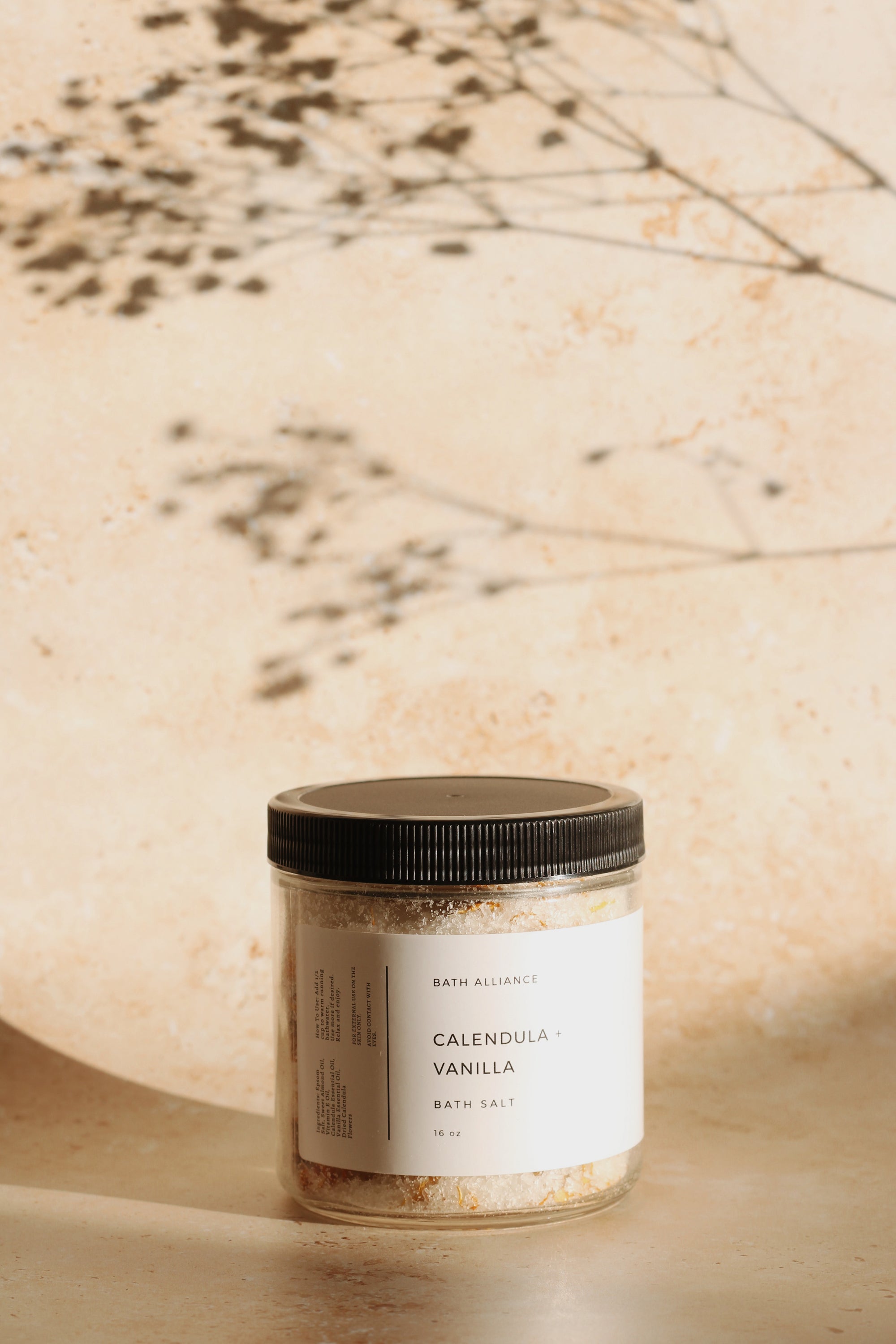 A jar of Calendula + Vanilla Bath Salt with dried calendula flowers, showcasing its natural ingredients and soothing properties.