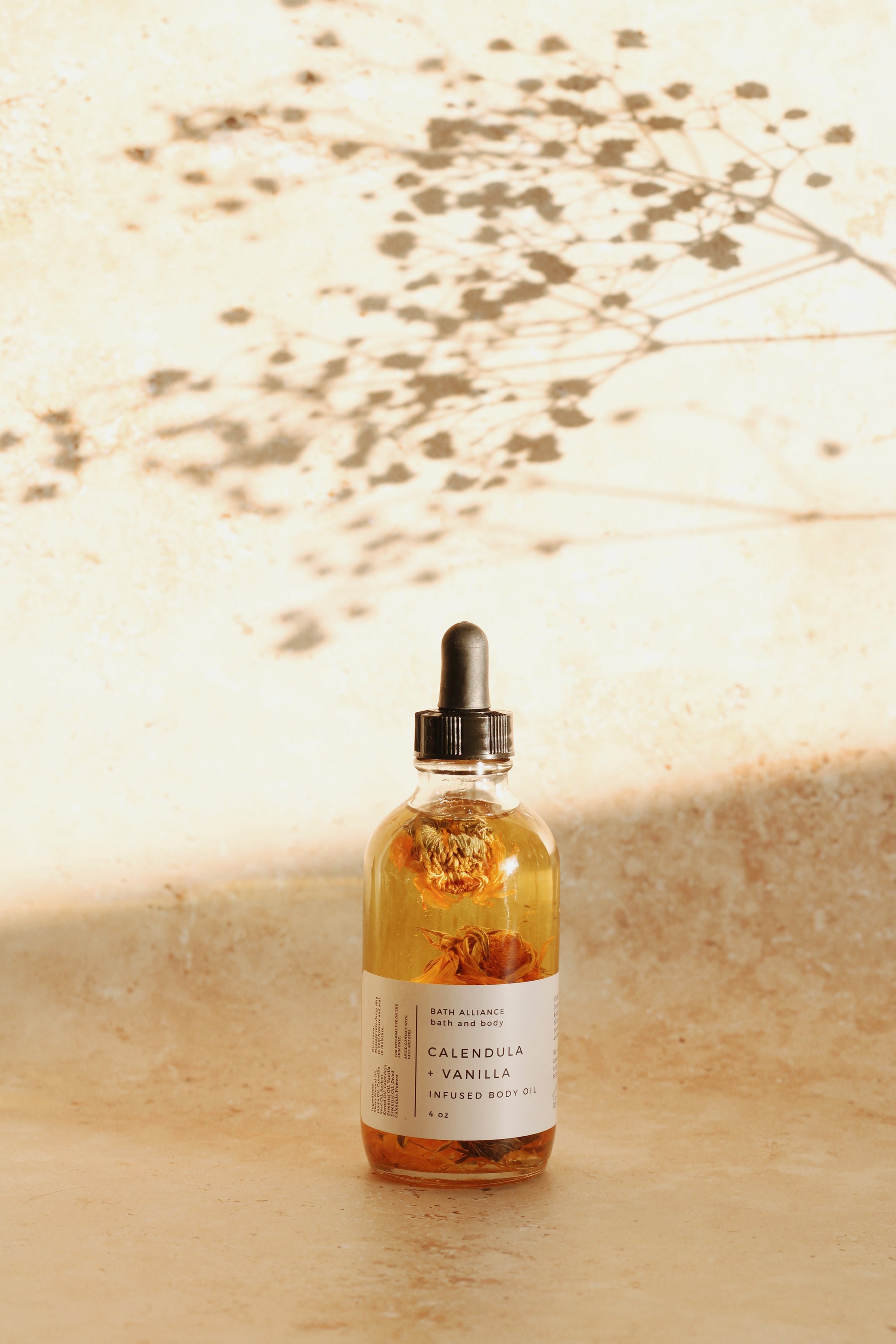 A bottle of Calendula + Vanilla Body Oil with a soothing blend of natural oils, featuring a floral design and a wooden cap.