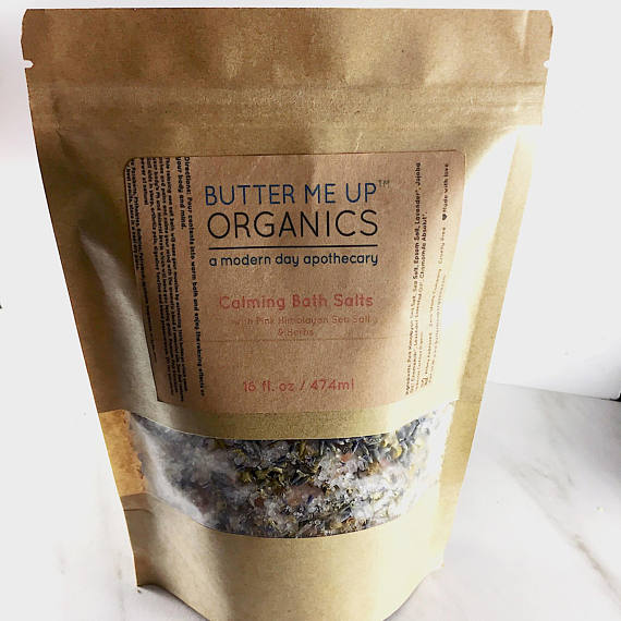 A resealable kraft glassine bag filled with Calming Bath Salts, featuring a blend of Epsom, Pink Himalayan, and Sea Salts, infused with lavender and chamomile.