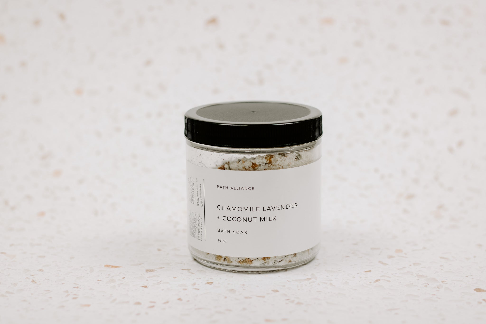 A jar of Chamomile Lavender + Coconut Milk Bath Soak with dried lavender buds and coconut milk powder, showcasing its natural ingredients.