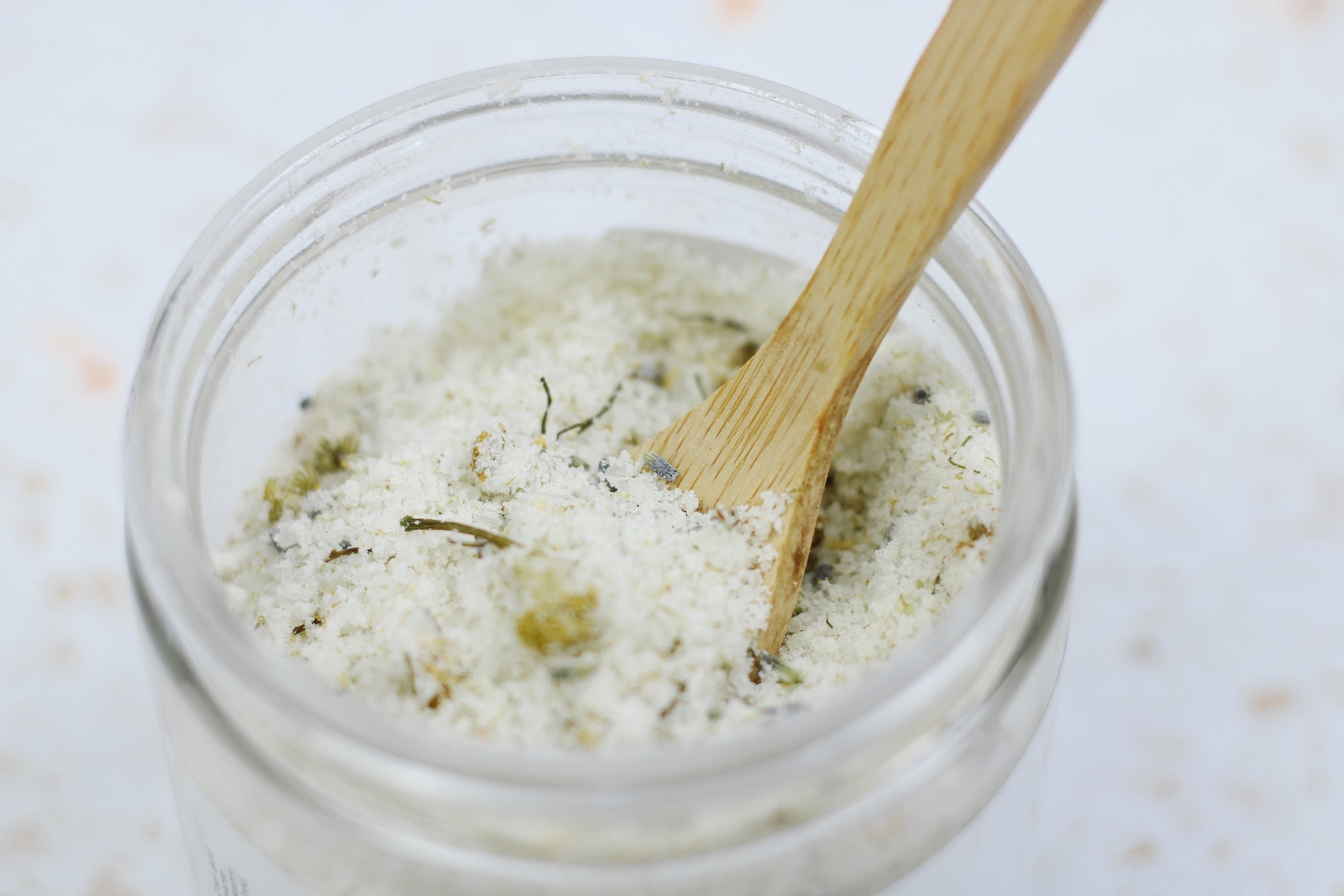 A jar of Chamomile Lavender + Coconut Milk Bath Soak with dried lavender buds and coconut milk powder, showcasing its natural ingredients.