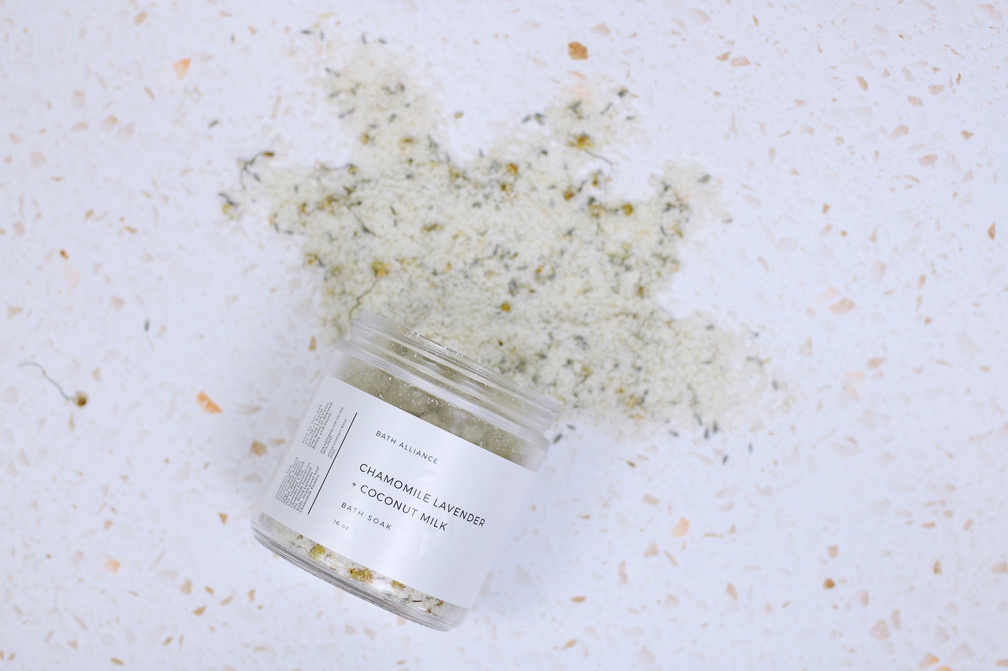 A jar of Chamomile Lavender + Coconut Milk Bath Soak with dried lavender buds and coconut milk powder, showcasing its natural ingredients.