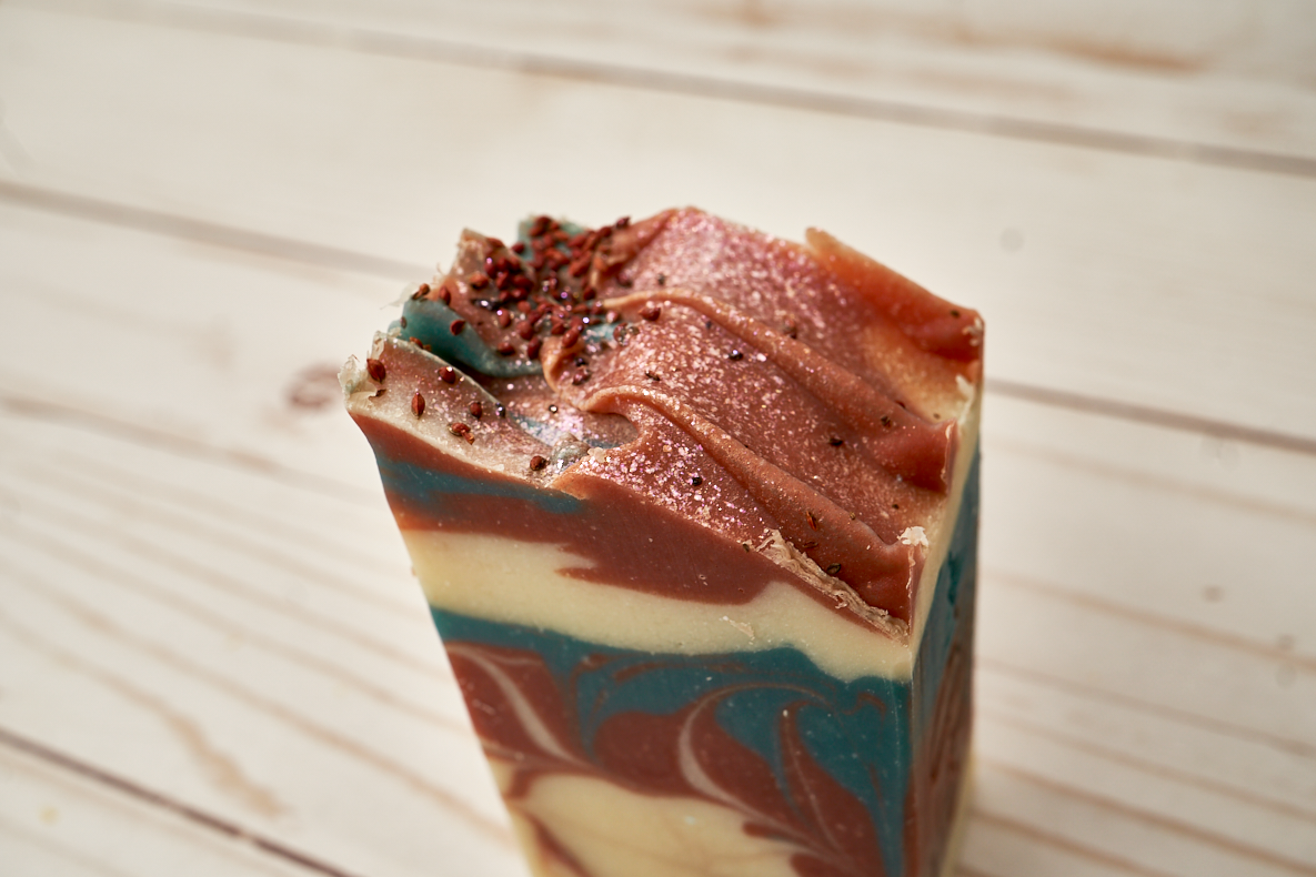 A beautifully crafted bar of Cranberry Fig Soap with vibrant colors and a festive design, showcasing its natural ingredients and eco-friendly glitter.