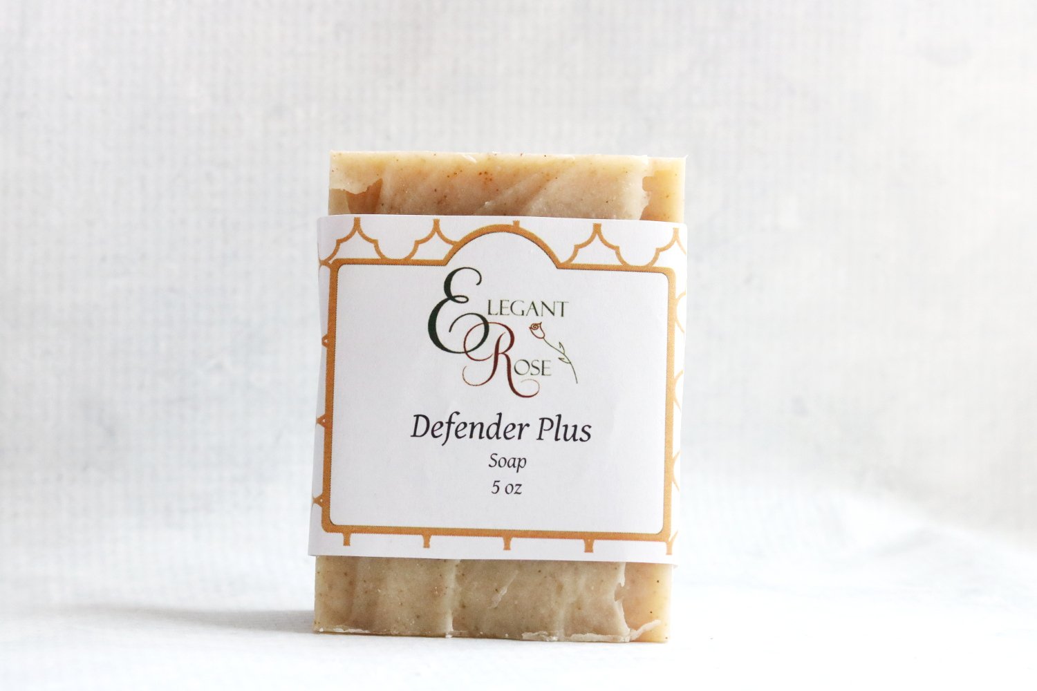 Defender PLUS Soap bar with natural ingredients, featuring essential oils and powders of frankincense and myrrh, displayed on a rustic wooden background.