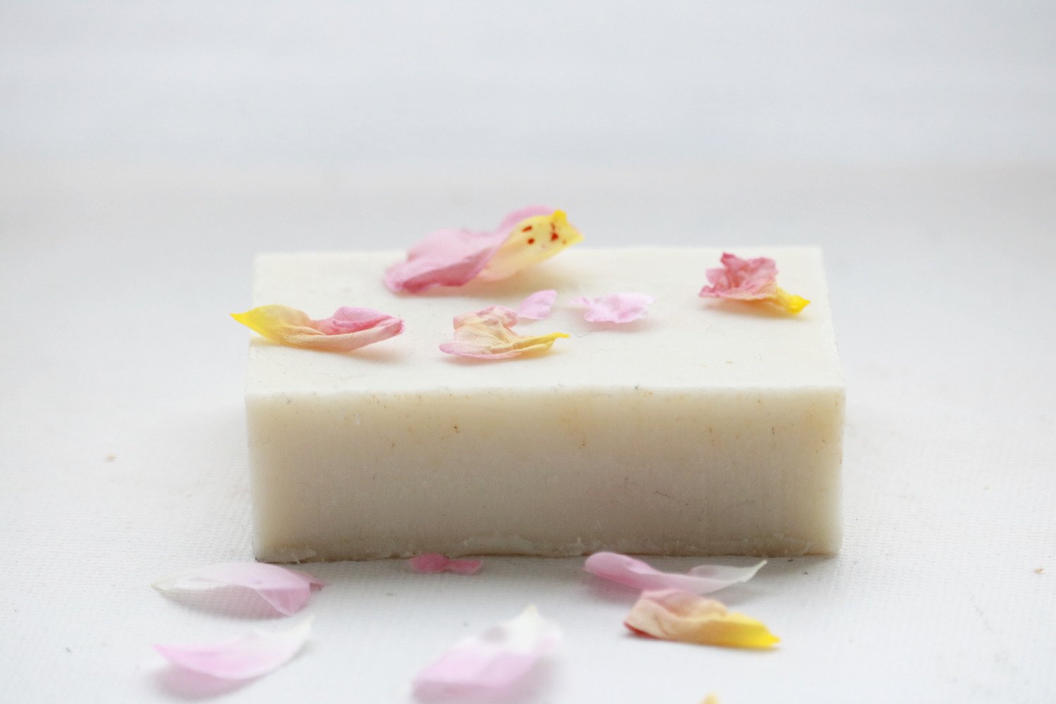 A luxurious bar of English Rose Soap infused with fresh garden roses, showcasing its delicate pink hue and rich texture.