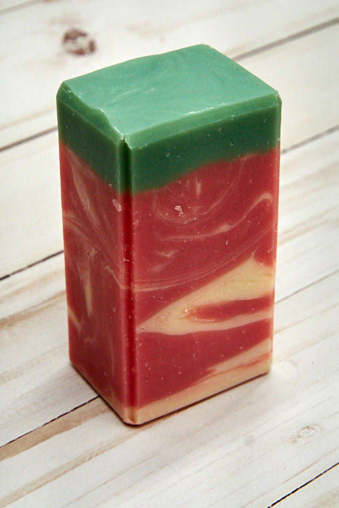 A bar of Fresh-Picked Strawberries Soap showcasing its vibrant color and texture, surrounded by fresh strawberries.