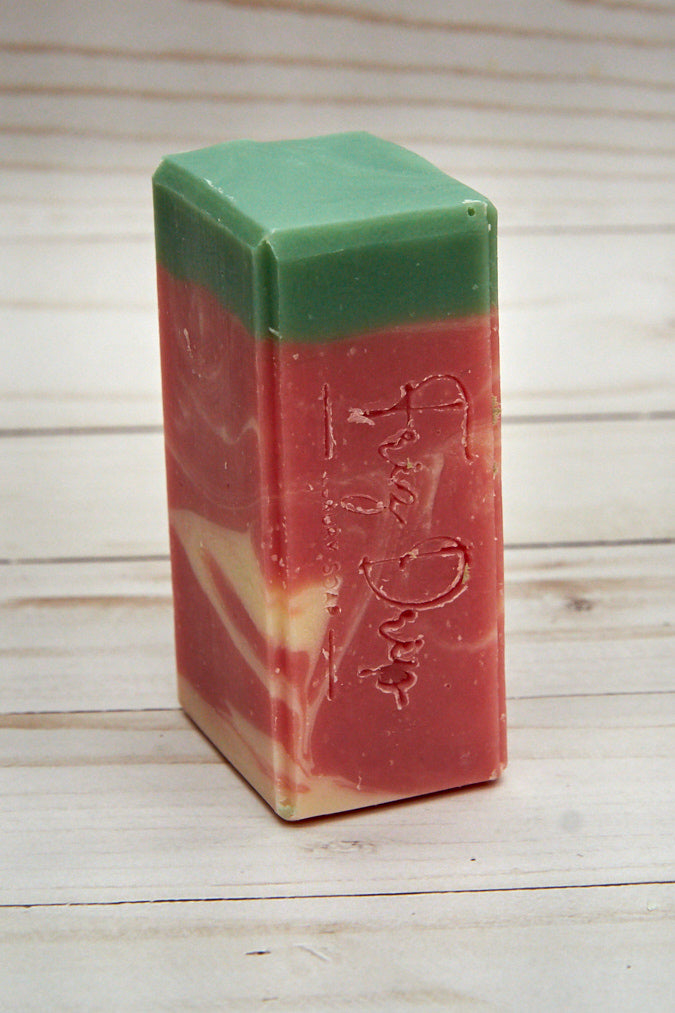 A bar of Fresh-Picked Strawberries Soap showcasing its vibrant color and texture, surrounded by fresh strawberries.