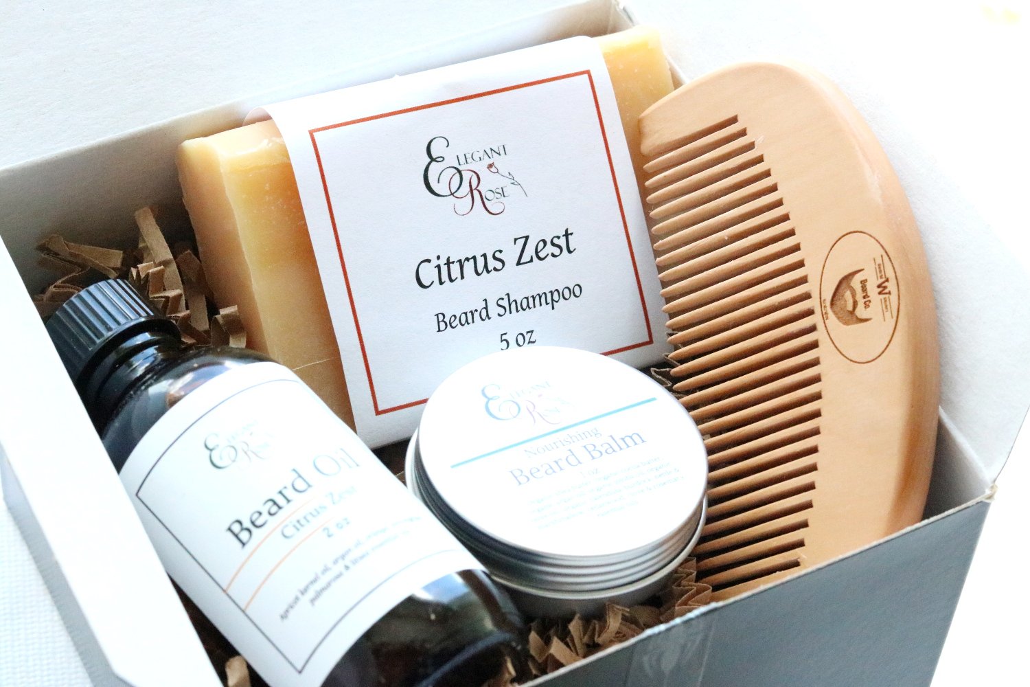 Beard grooming kit featuring beard oil, shampoo bar, balm, and wooden comb in a black gift box.