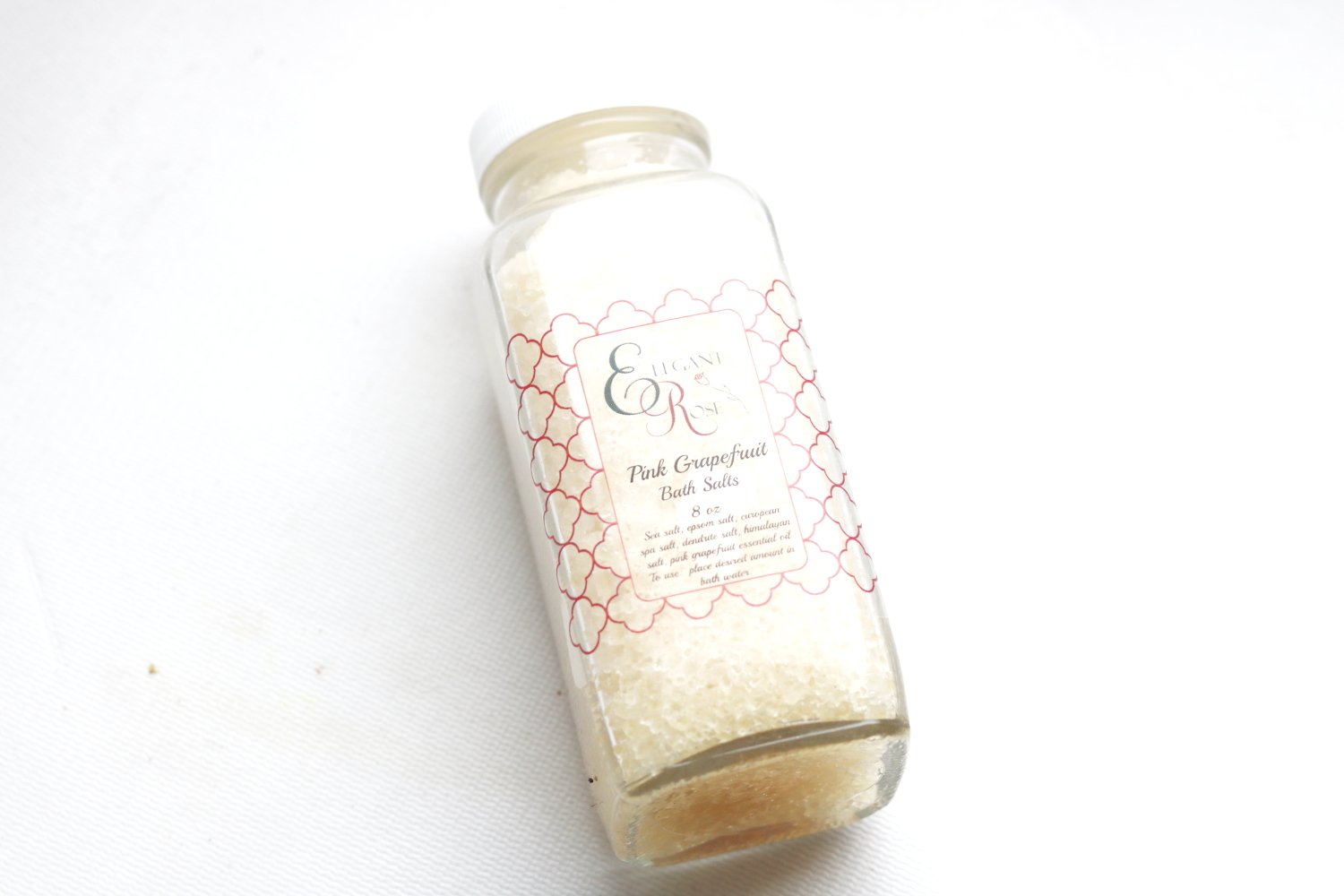 An 8 oz. jar of Grapefruit Bath Salts with a vibrant label, surrounded by scattered bath salts and grapefruit slices, showcasing a relaxing spa atmosphere.