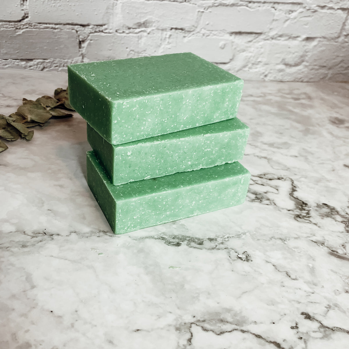 A vibrant green tea verbena scrub bar with sea salt exfoliant, showcasing its unique handcrafted design and refreshing citrus scent.