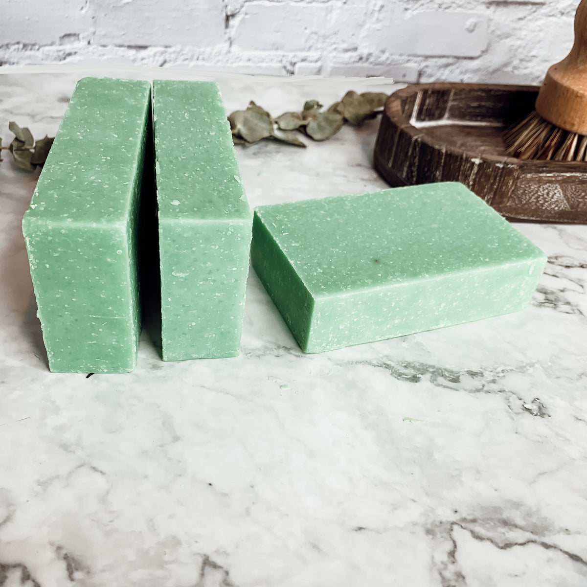 A vibrant green tea verbena scrub bar with sea salt exfoliant, showcasing its unique handcrafted design and refreshing citrus scent.