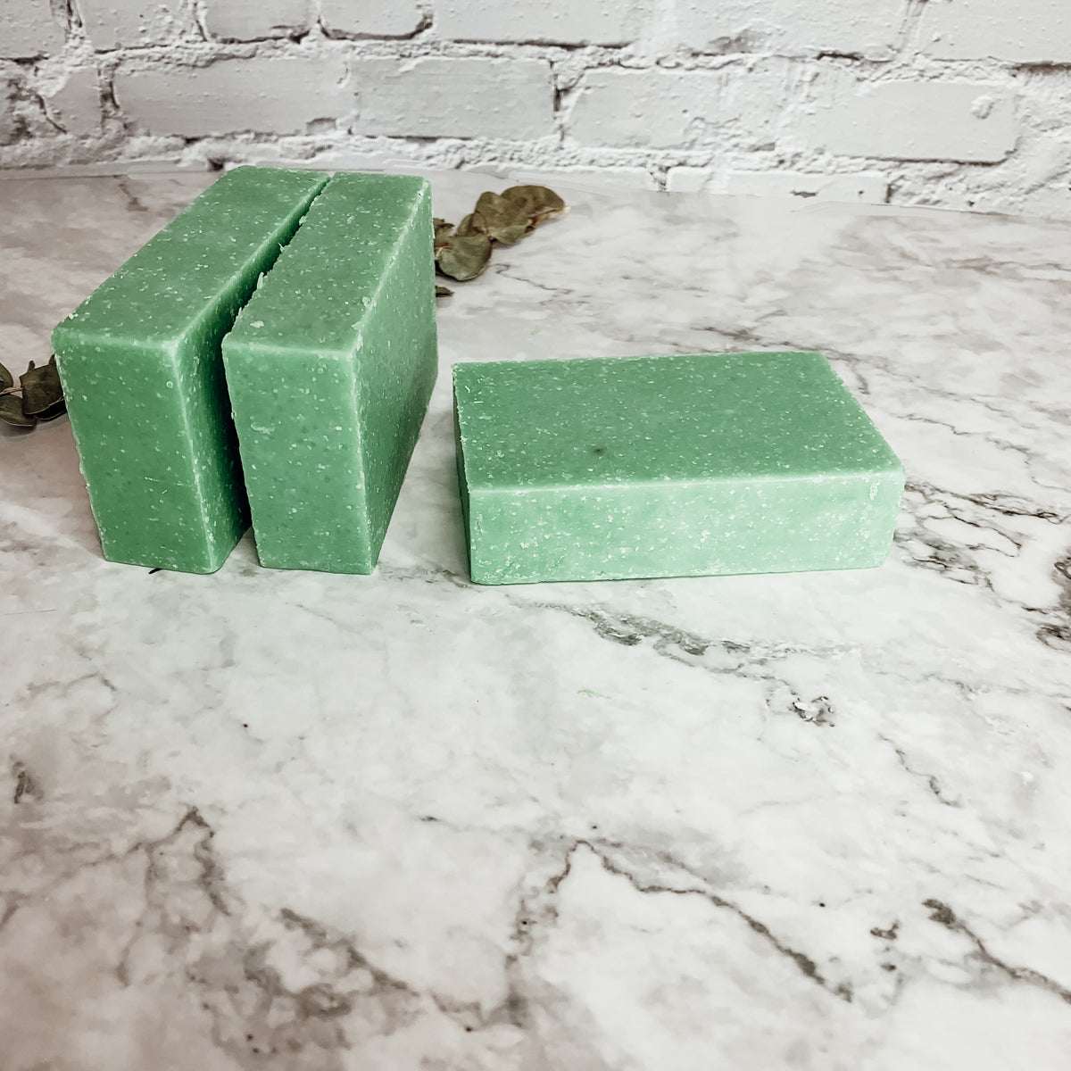 A vibrant green tea verbena scrub bar with sea salt exfoliant, showcasing its unique handcrafted design and refreshing citrus scent.