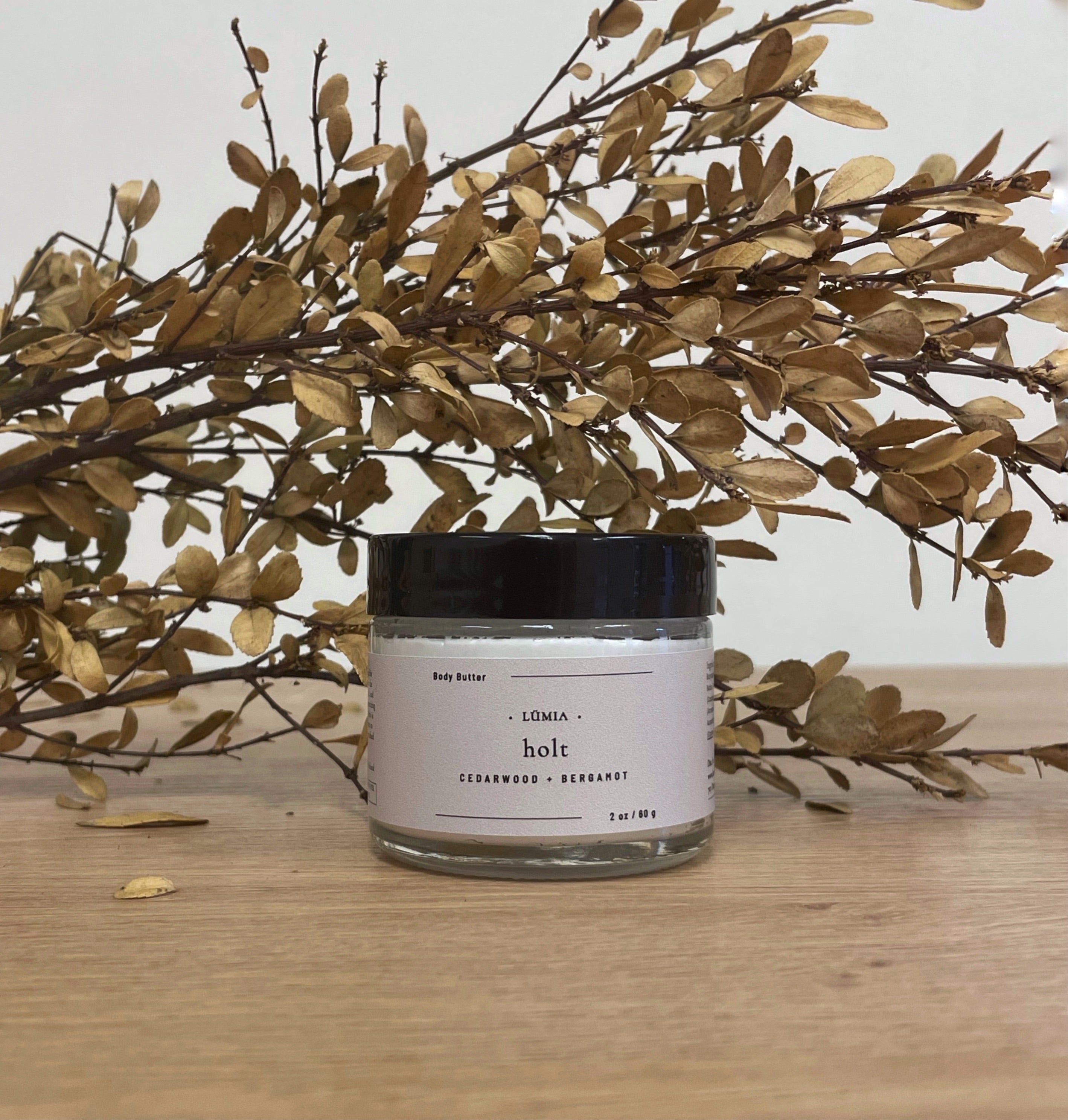 Holt Whipped Body Butter in a jar, showcasing its creamy texture and natural ingredients, surrounded by citrus fruits and cedarwood.