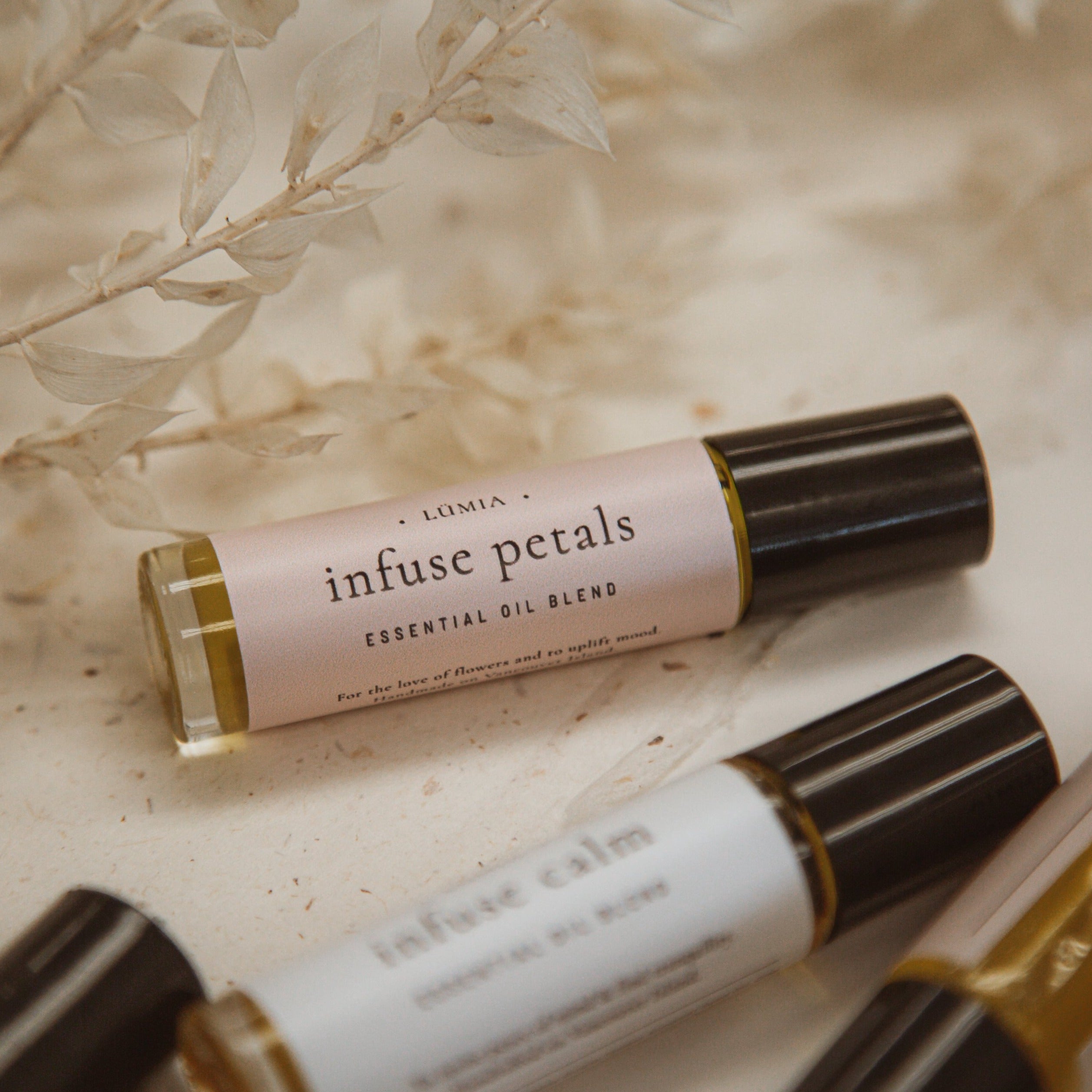 A bottle of Infuse Petals essential oil blend featuring floral scents of Clary Sage, Ylang-Ylang, and Rose Geranium, designed for emotional restoration.