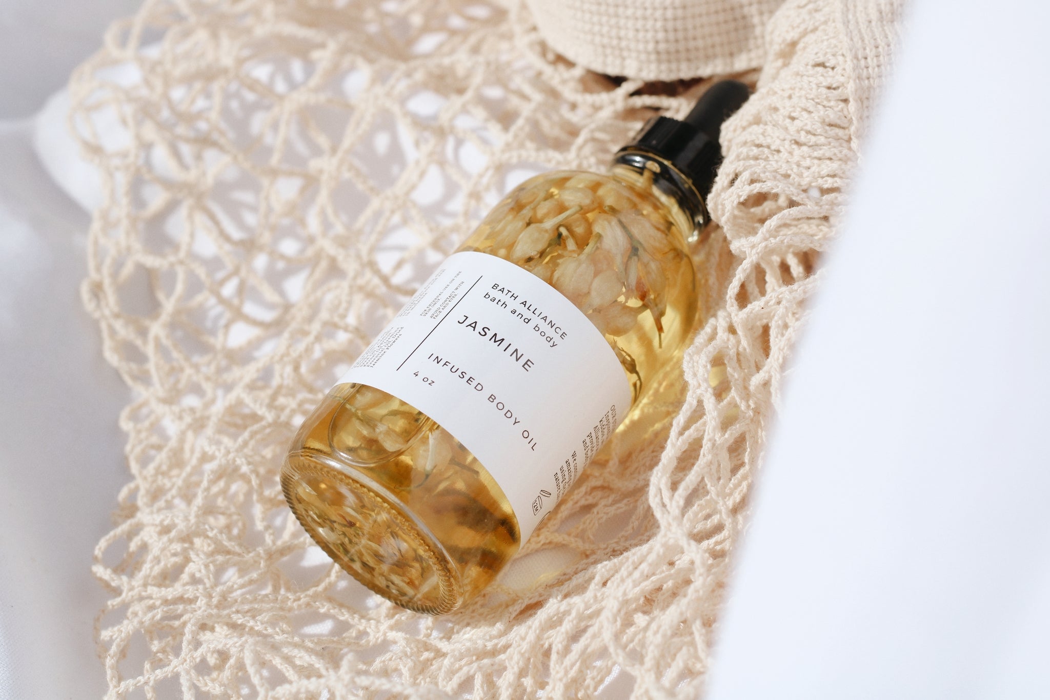 A luxurious jar of Jasmine Body Oil featuring a blend of natural oils, surrounded by dried jasmine flowers.