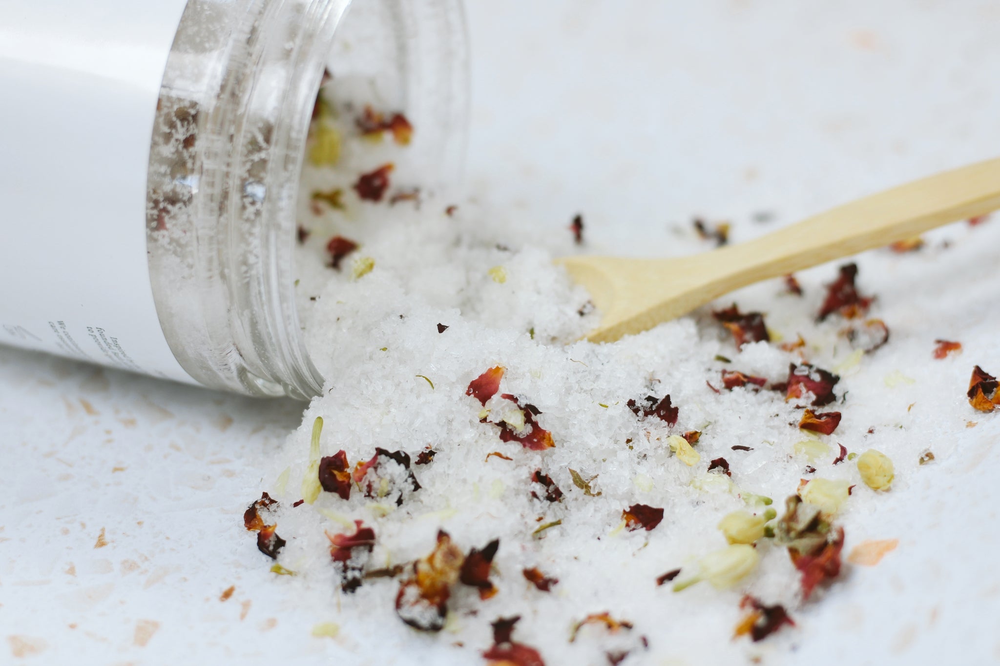 A beautifully arranged jar of Jasmine + Rose Bath Salt with dried rose petals and jasmine flower buds, showcasing its natural ingredients.