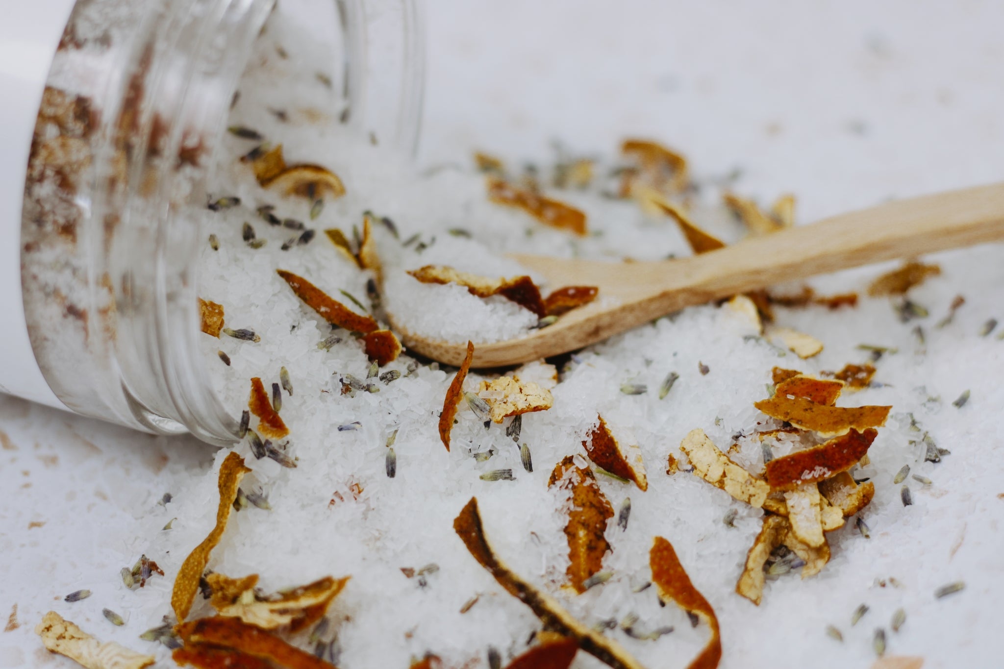 A jar of Lavender + Sweet Orange Bath Salt with dried lavender buds and orange peels, showcasing its natural ingredients.