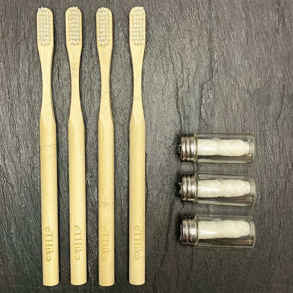 A complete Oral Hygiene Kit featuring four bamboo toothbrushes and three mint dental flosses in a glass jar, all 100% natural and eco-friendly.