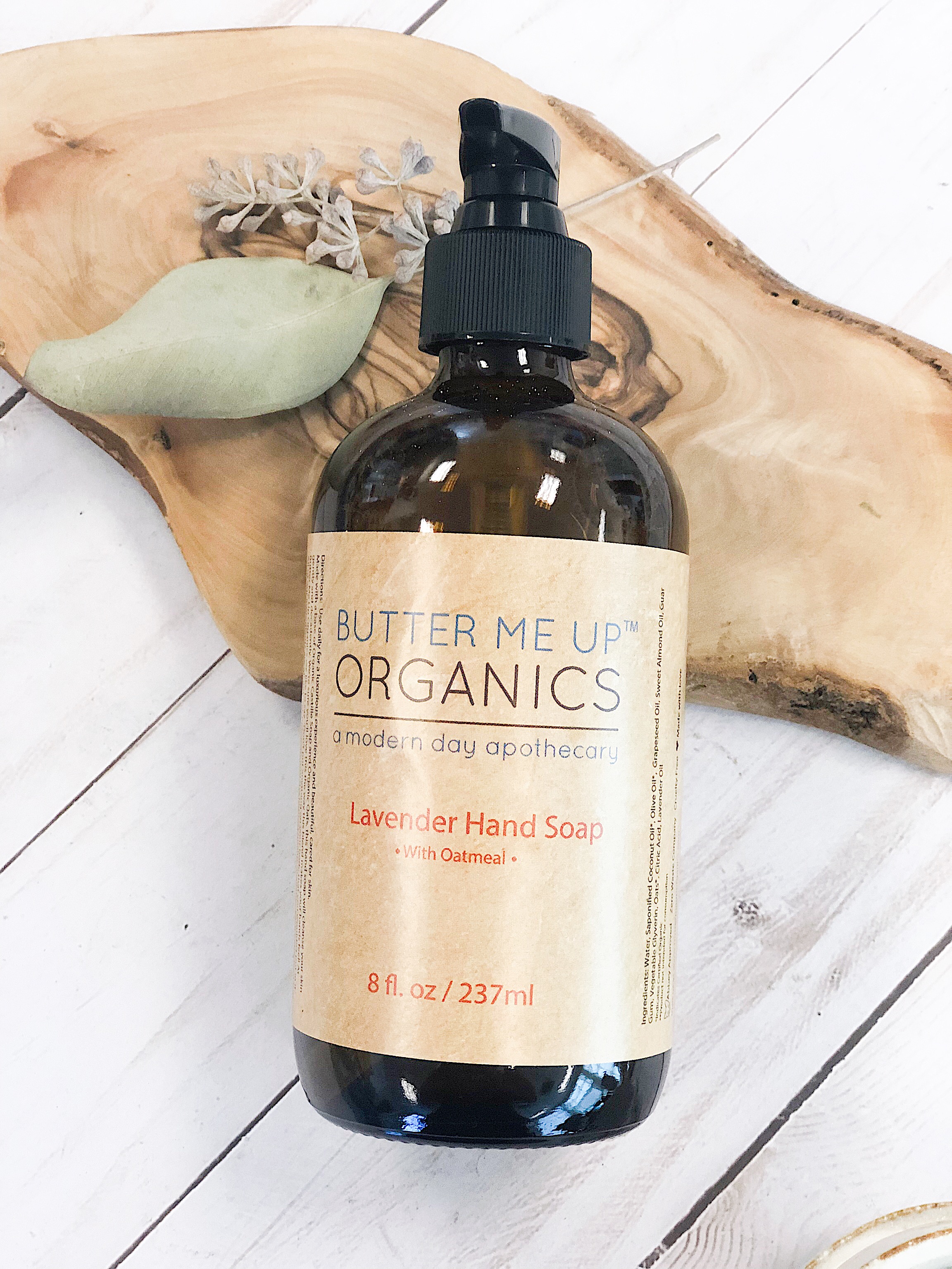 A bar of Organic Oatmeal Hand Soap with visible oats and a lavender hue, resting on a wooden surface, showcasing its natural ingredients.