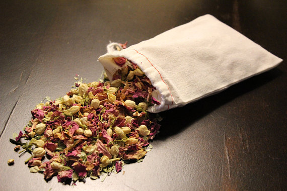 A beautifully arranged sachet of Organic Rejuvenating Bath Tea, featuring vibrant herbs and flowers like Jasmine, Lemon Peel, and Pink Rose Petals, set against a calming background.