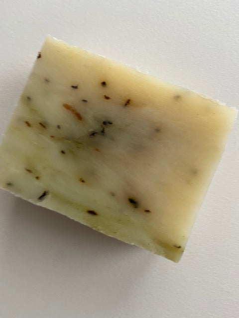 A bar of Peppermint Tea Tree Soap with visible peppermint leaves, showcasing its natural ingredients and creamy texture.