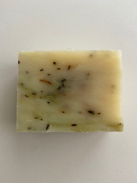 A bar of Peppermint Tea Tree Soap with visible peppermint leaves, showcasing its natural ingredients and creamy texture.