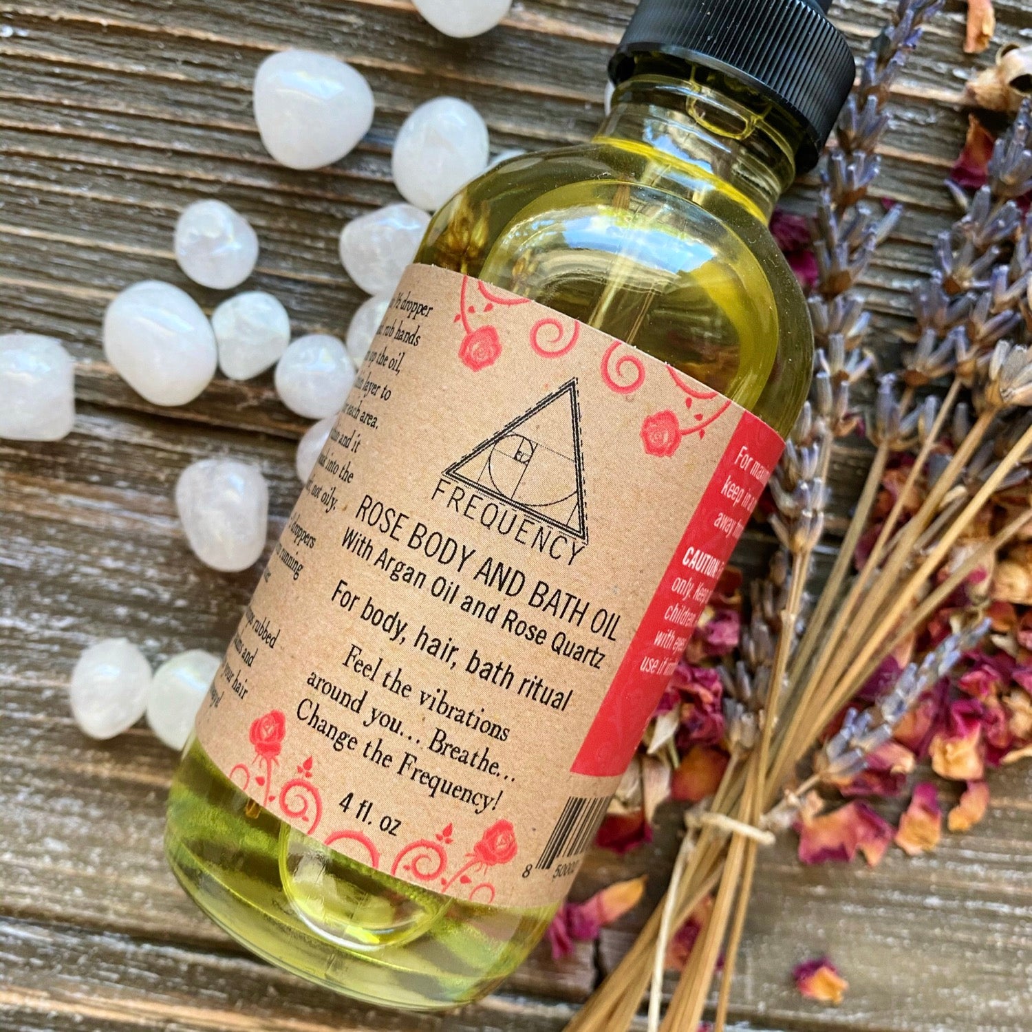 A 4 fl oz glass bottle of Rose Body, Hair & Bath Oil with a dropper, showcasing its luxurious blend of nourishing oils and rose quartz crystals.