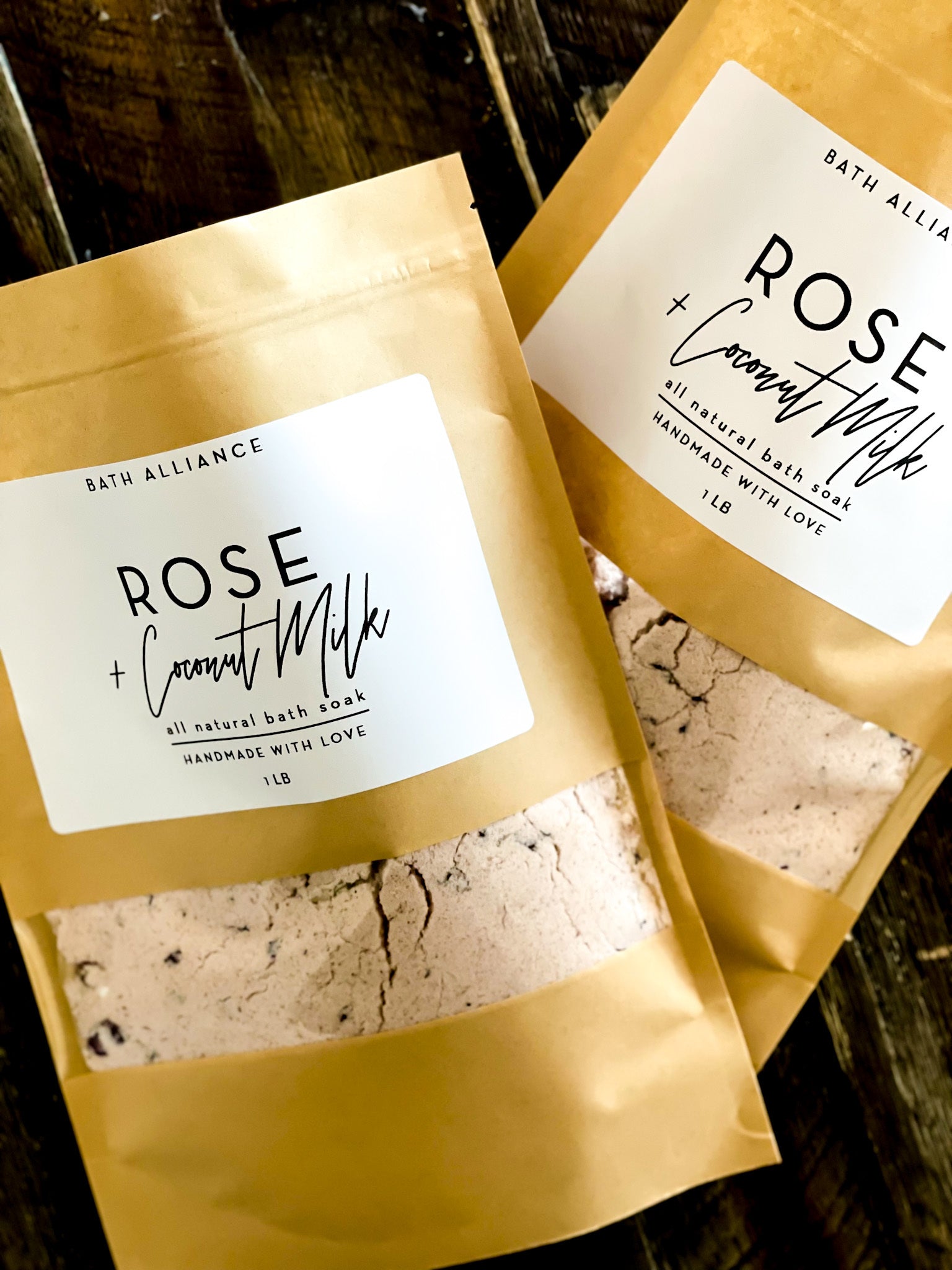 A resealable kraft pouch filled with Rose + Coconut Milk Bath Soak, featuring dried rose petals and pink Himalayan salt.